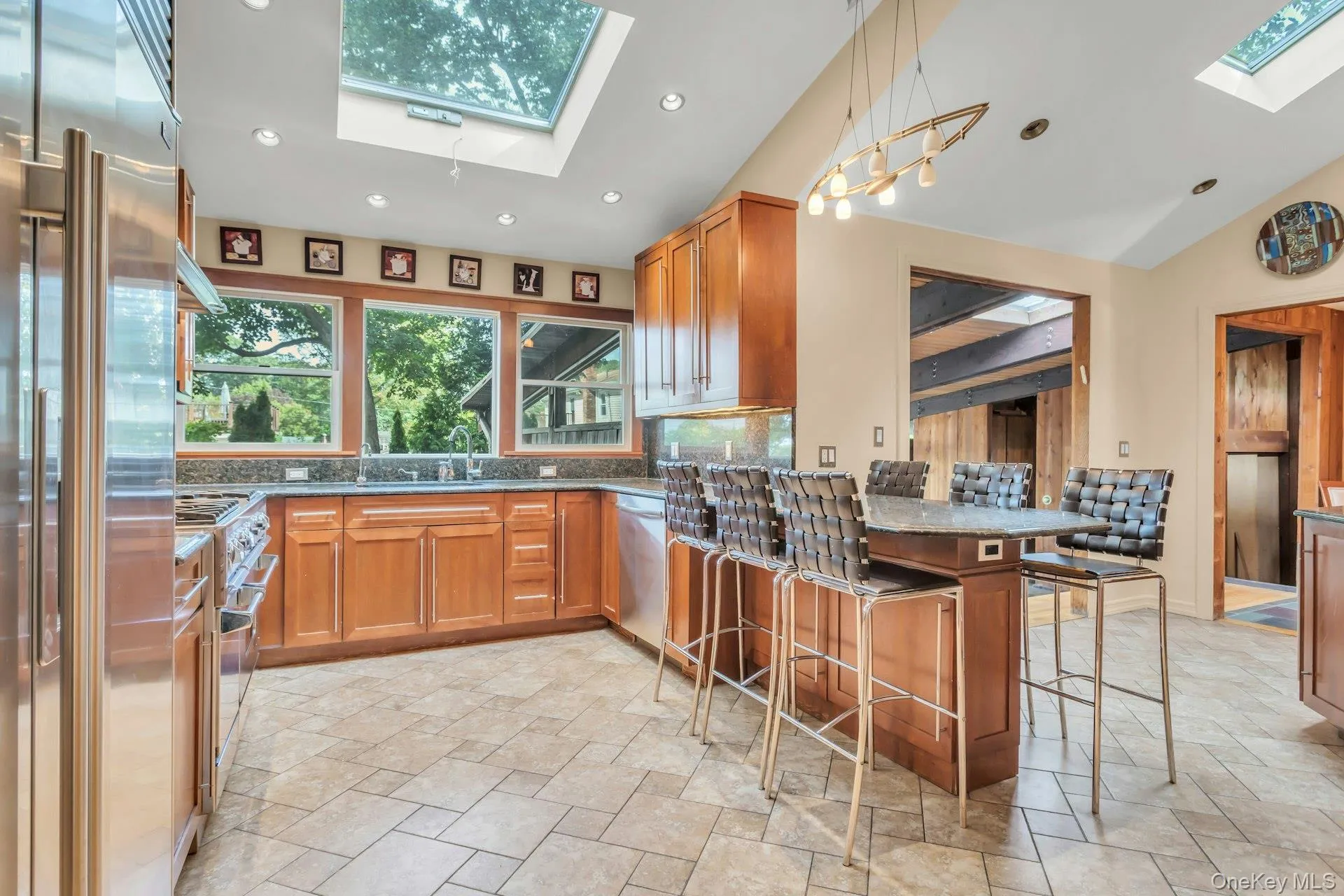 Skylit kitchen with wood cabinetry, stainless steel appliances, granite countertops, and tile flooring Skylit kitchen with wood cabinetry, stainless steel appliances, granite countertops, and tile flooring