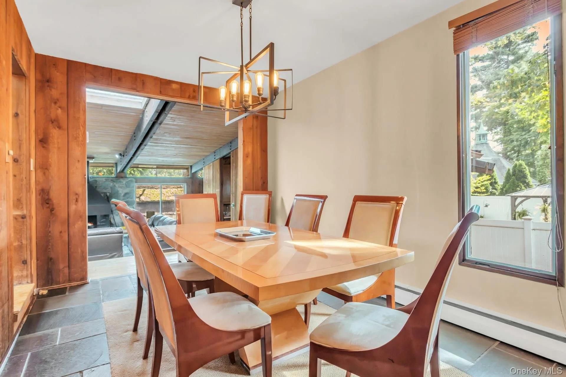 Recessed lighting, wood-paneled wall, stone tile flooring, modern chandelier, and large window Recessed lighting, wood-paneled wall, stone tile flooring, modern chandelier, and large window