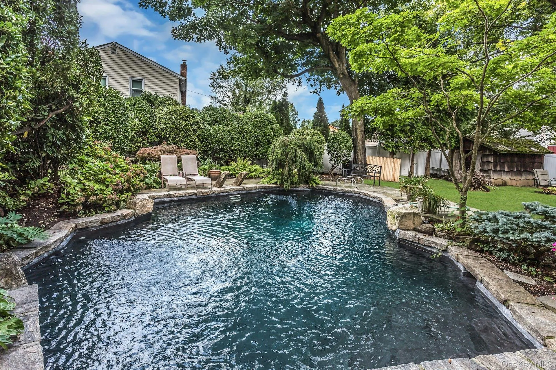 In-ground pool with stone coping, surrounded by mature landscaping and natural stone patio In-ground pool with stone coping, surrounded by mature landscaping and natural stone patio