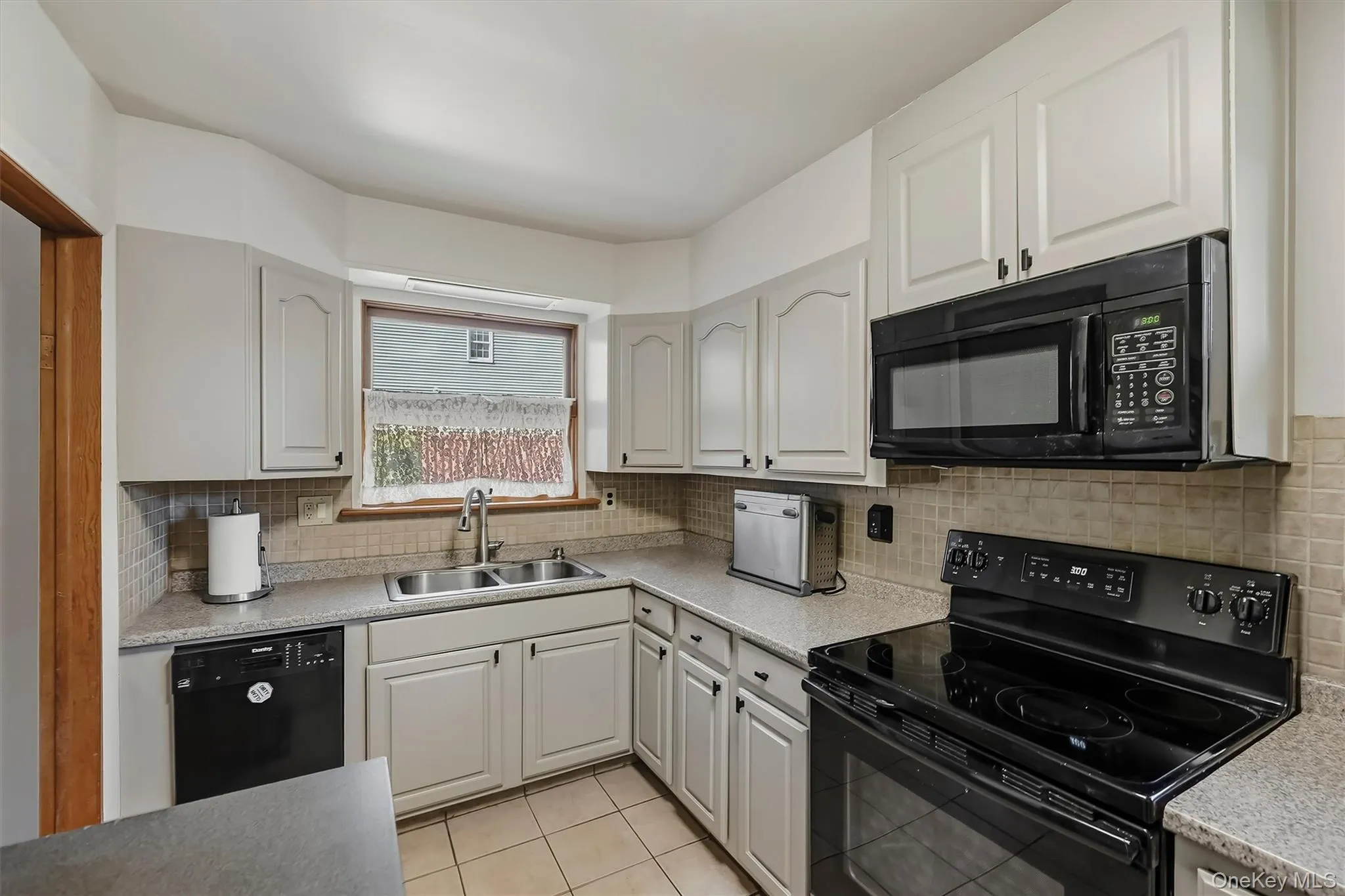 Double stainless steel sink with tiled backsplash and tiled flooring for easy cleanup Double stainless steel sink with tiled backsplash and tiled flooring for easy cleanup
