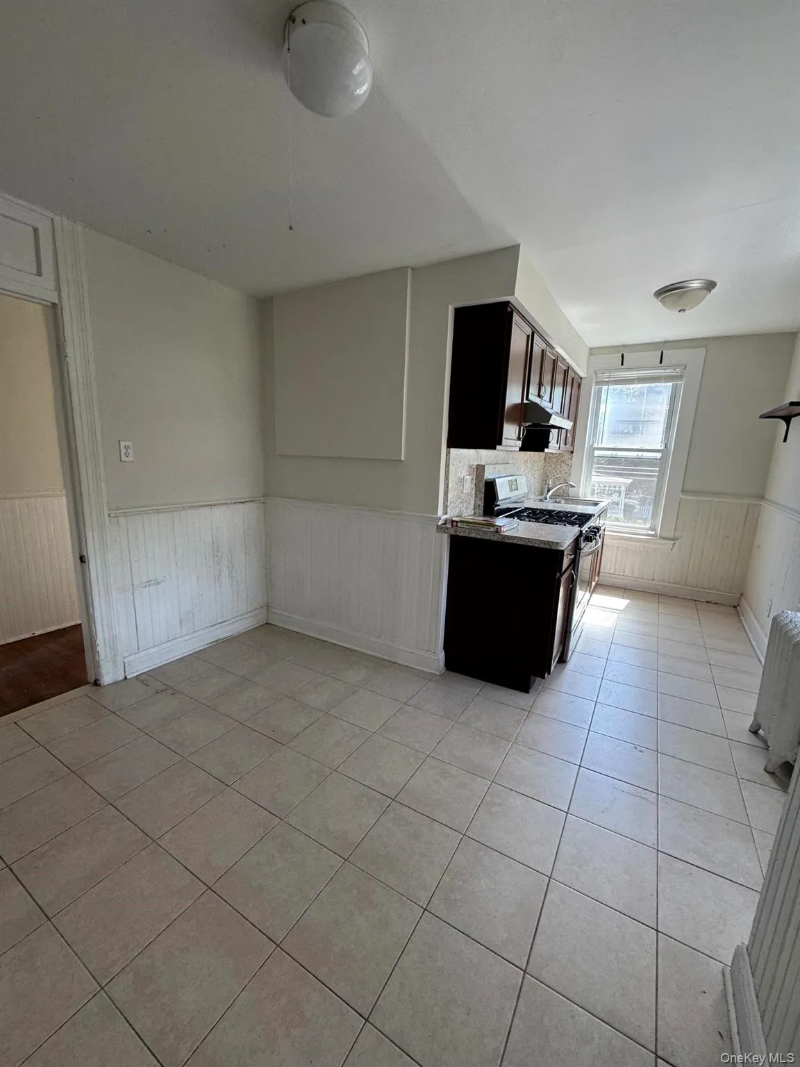Kitchen featuring tile flooring, dark wood-finish cabinetry, a stainless steel range, and a window Kitchen featuring tile flooring, dark wood-finish cabinetry, a stainless steel range, and a window