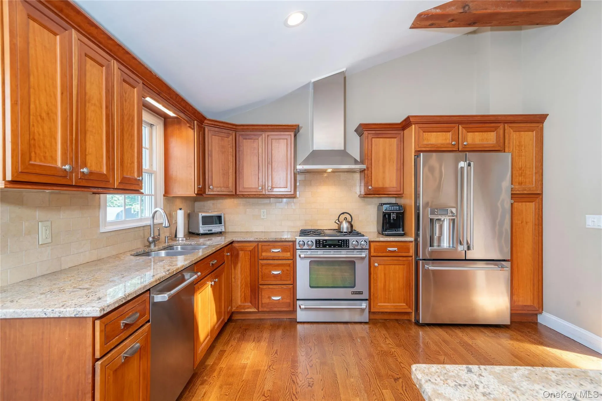 Warm wood custom cabinetry, granite countertops and stainless-steel appliances complement the kitchen's generous workspace, while hardwood floors maintain the seamless flow of the main living level. Warm wood custom cabinetry, granite countertops and stainless-steel appliances complement the kitchen's generous workspace, while hardwood floors maintain the seamless flow of the main living level.