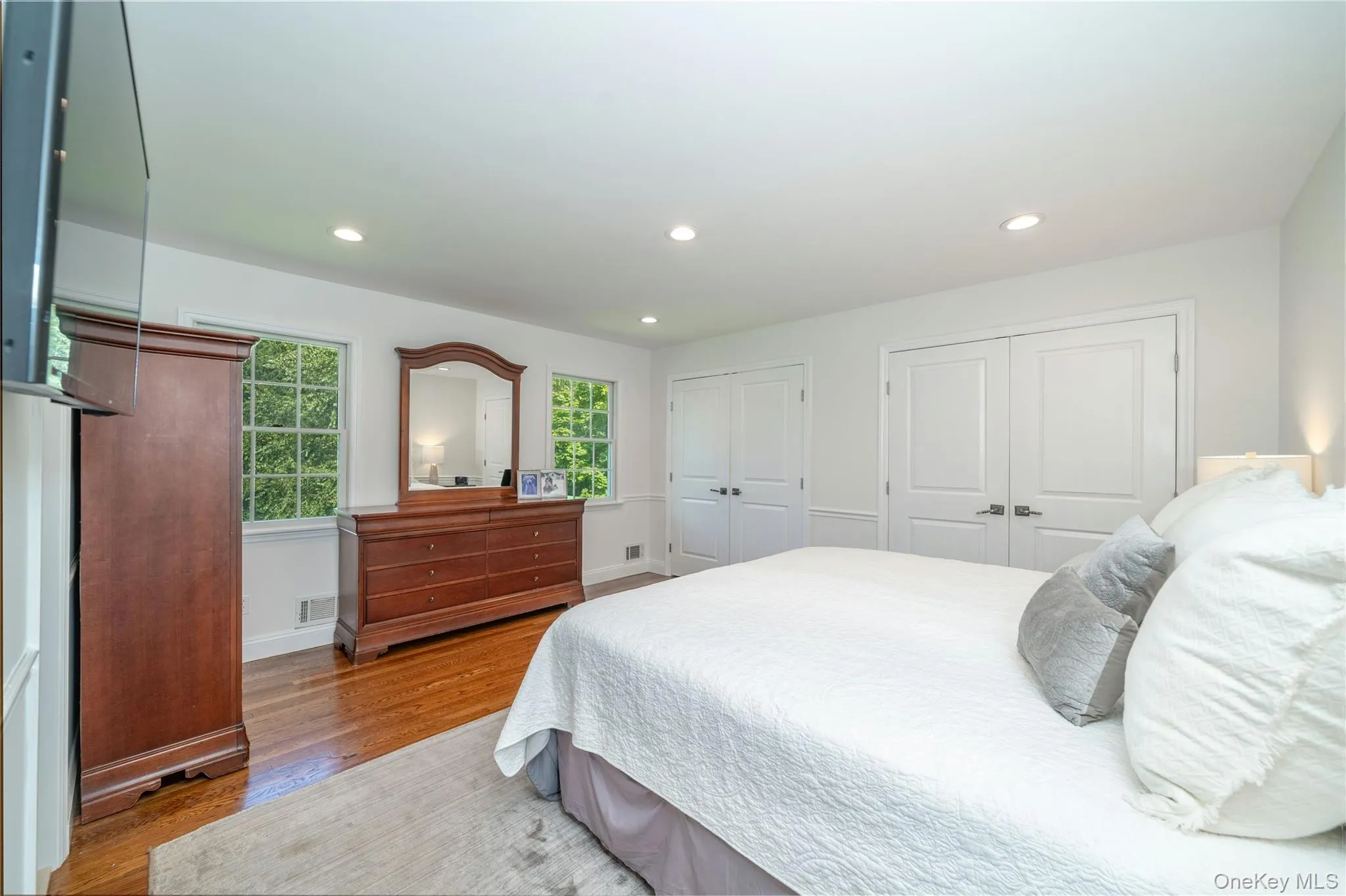 A second view highlights the primary bedroom's peaceful, tree-lined outlook with no neighboring homes in sight, along with two double closets featuring custom built-ins. A second view highlights the primary bedroom's peaceful, tree-lined outlook with no neighboring homes in sight, along with two double closets featuring custom built-ins.