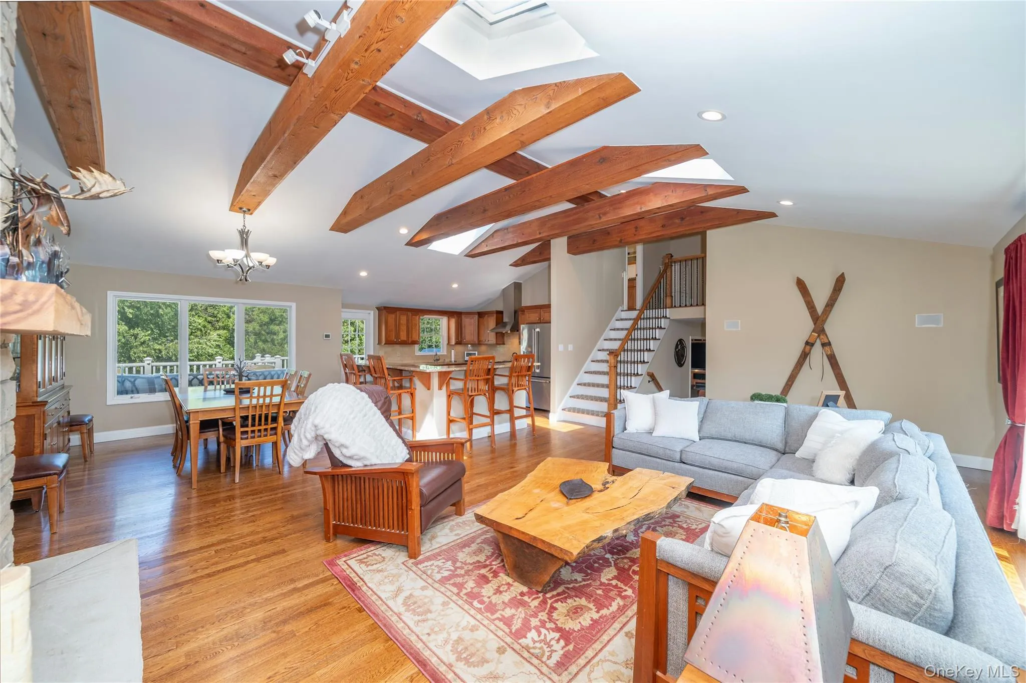 A second view highlights the impressive scale of the living area, where soaring beamed ceilings, abundant natural light and the stone fireplace create a dramatic yet comfortable gathering space. A second view highlights the impressive scale of the living area, where soaring beamed ceilings, abundant natural light and the stone fireplace create a dramatic yet comfortable gathering space.