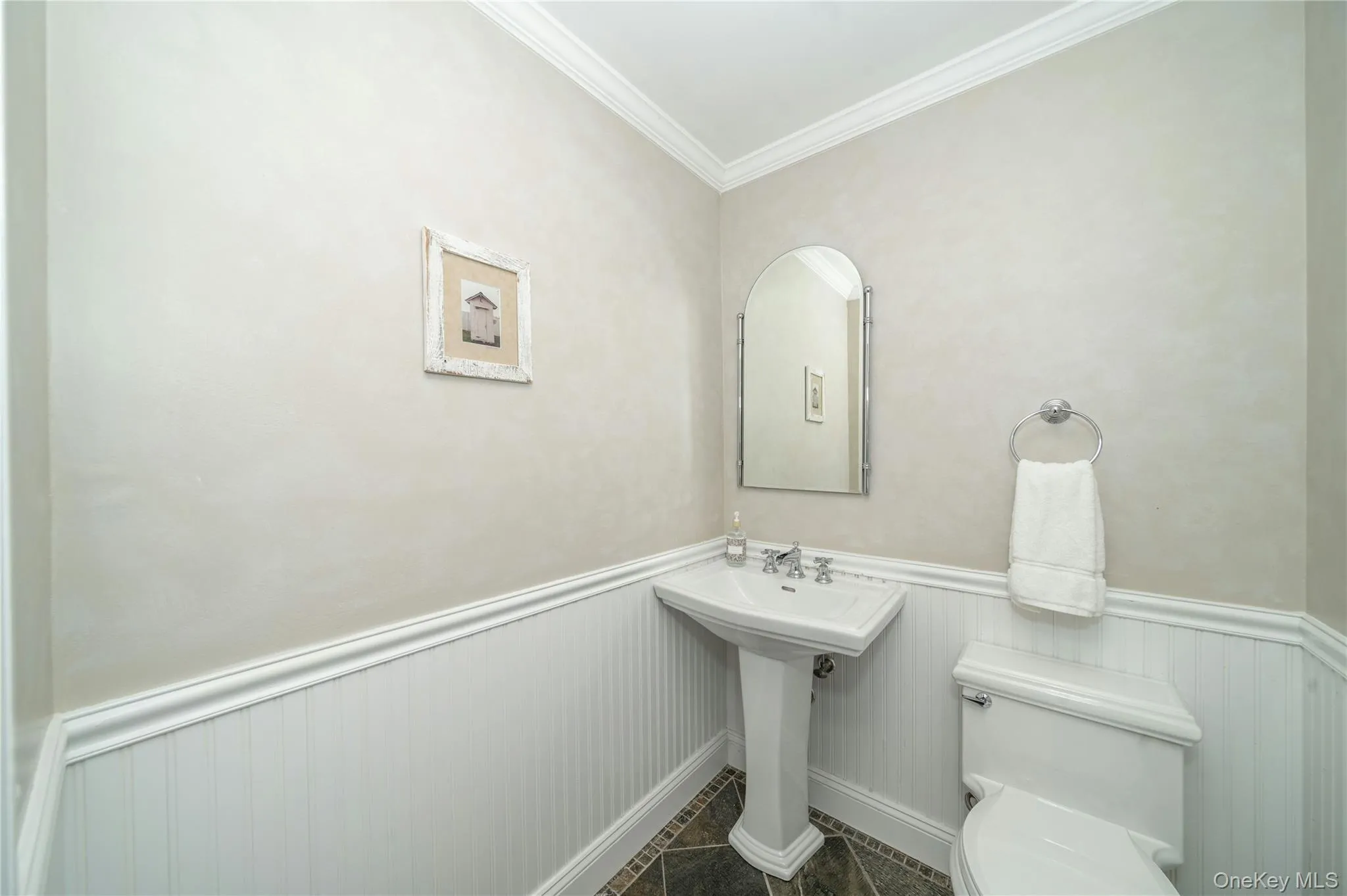 Conveniently located just off the family room, the powder room features classic wainscoting and a pedestal sink. Conveniently located just off the family room, the powder room features classic wainscoting and a pedestal sink.