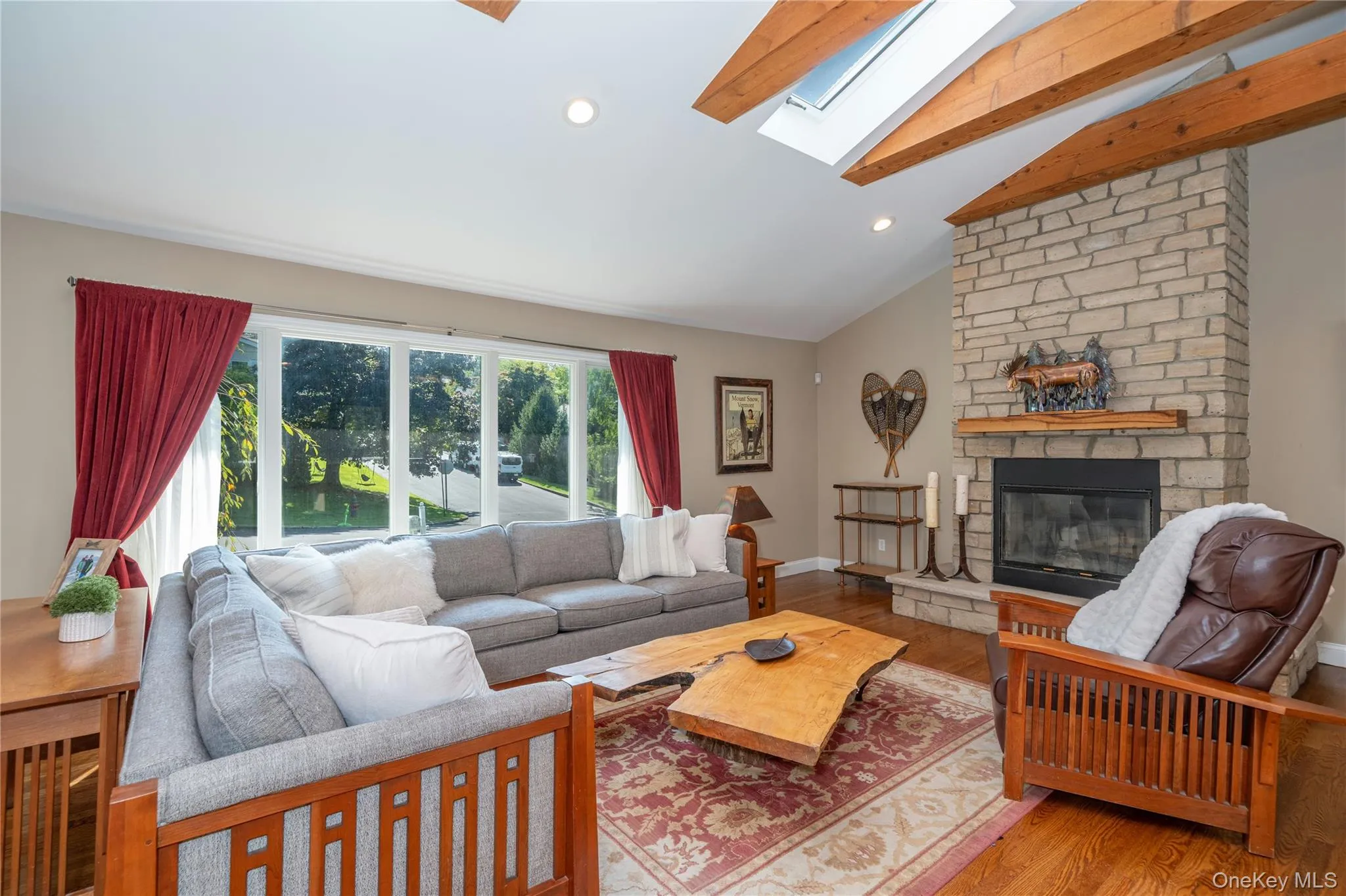 The stone fireplace creates a striking focal point in the living room, complemented by warm wood details and the home's distinctive exposed beams. The stone fireplace creates a striking focal point in the living room, complemented by warm wood details and the home's distinctive exposed beams.