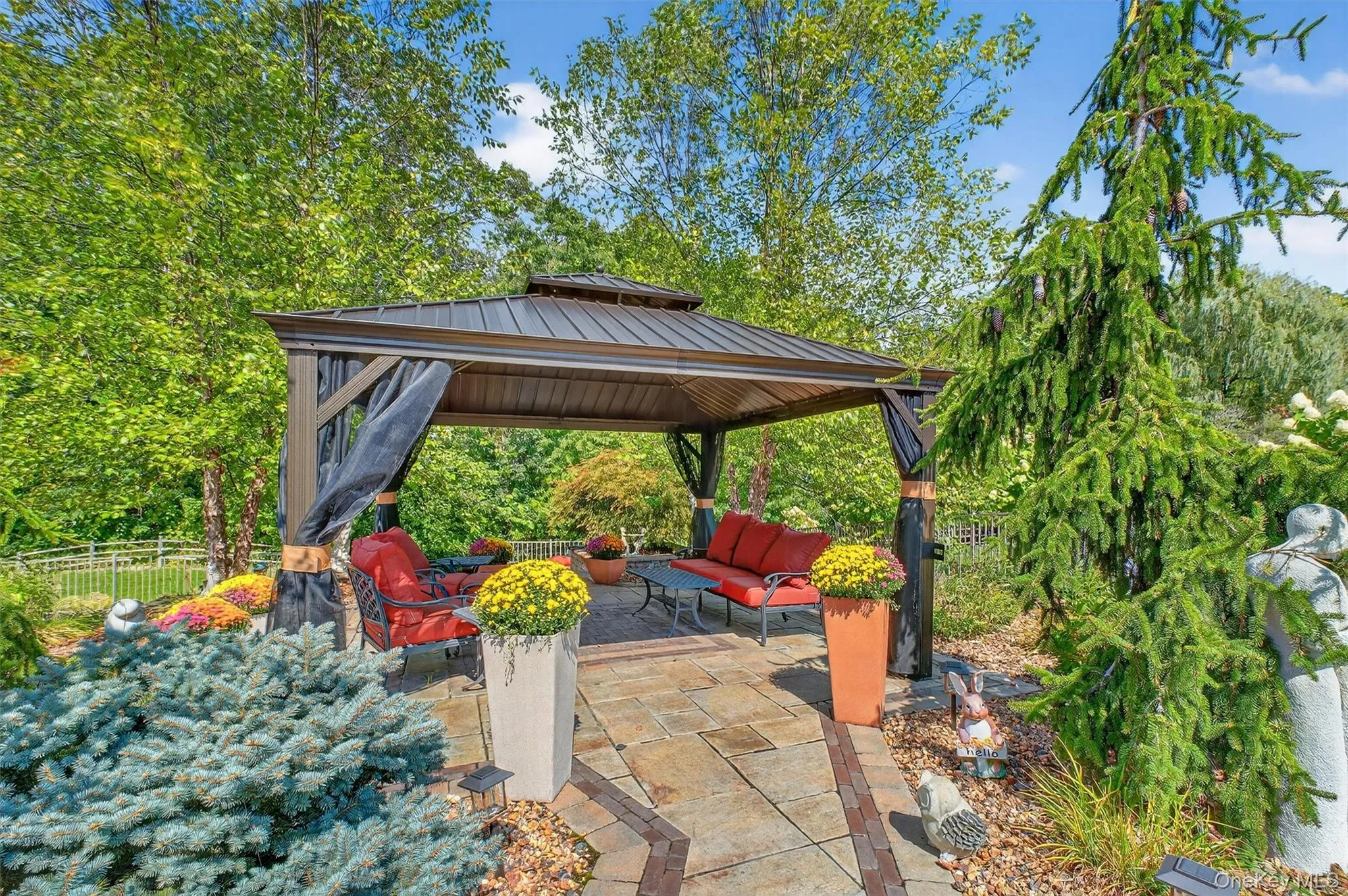 Perched just above the firepit area, a freestanding, maintenance-free aluminum gazebo anchors an additional outdoor living space designed for year-round enjoyment. Set on stone pavers , this spacious retreat offers the perfect shaded spot for relaxing with a cocktail, enjoying a cigar, or hosting guests in comfort. Its open-air design captures the breeze while providing shelter, making it the ultimate complement to the backyard’s resort-inspired layout—a true entertainer’s extension of the home. Perched just above the firepit area, a freestanding, maintenance-free aluminum gazebo anchors an additional outdoor living space designed for year-round enjoyment. Set on stone pavers , this spacious retreat offers the perfect shaded spot for relaxing with a cocktail, enjoying a cigar, or hosting guests in comfort. Its open-air design captures the breeze while providing shelter, making it the ultimate complement to the backyard’s resort-inspired layout—a true entertainer’s extension of the home.