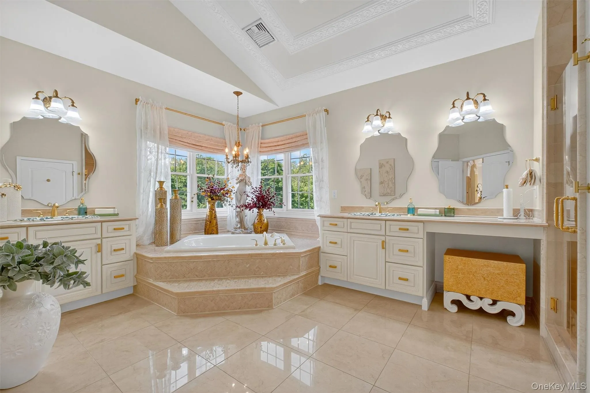 This master bathroom ensuite is a true sanctuary and the cherry on top of the master suite. The radiant limestone floor sets the stage for luxury, leading to a built-in platform soaking tub finished in a striking diamond-cut mosaic stone. Exquisitely stenciled floral fixtures add a sophisticated, artistic touch, while high-end lighting fills the space with a warm, inviting glow. Completing the look, stylish His & Her vanities with gold hardware blend timeless charm with modern refinement, making this bath a perfect extension of the suite’s elegance. This master bathroom ensuite is a true sanctuary and the cherry on top of the master suite. The radiant limestone floor sets the stage for luxury, leading to a built-in platform soaking tub finished in a striking diamond-cut mosaic stone. Exquisitely stenciled floral fixtures add a sophisticated, artistic touch, while high-end lighting fills the space with a warm, inviting glow. Completing the look, stylish His & Her vanities with gold hardware blend timeless charm with modern refinement, making this bath a perfect extension of the suite’s elegance.
