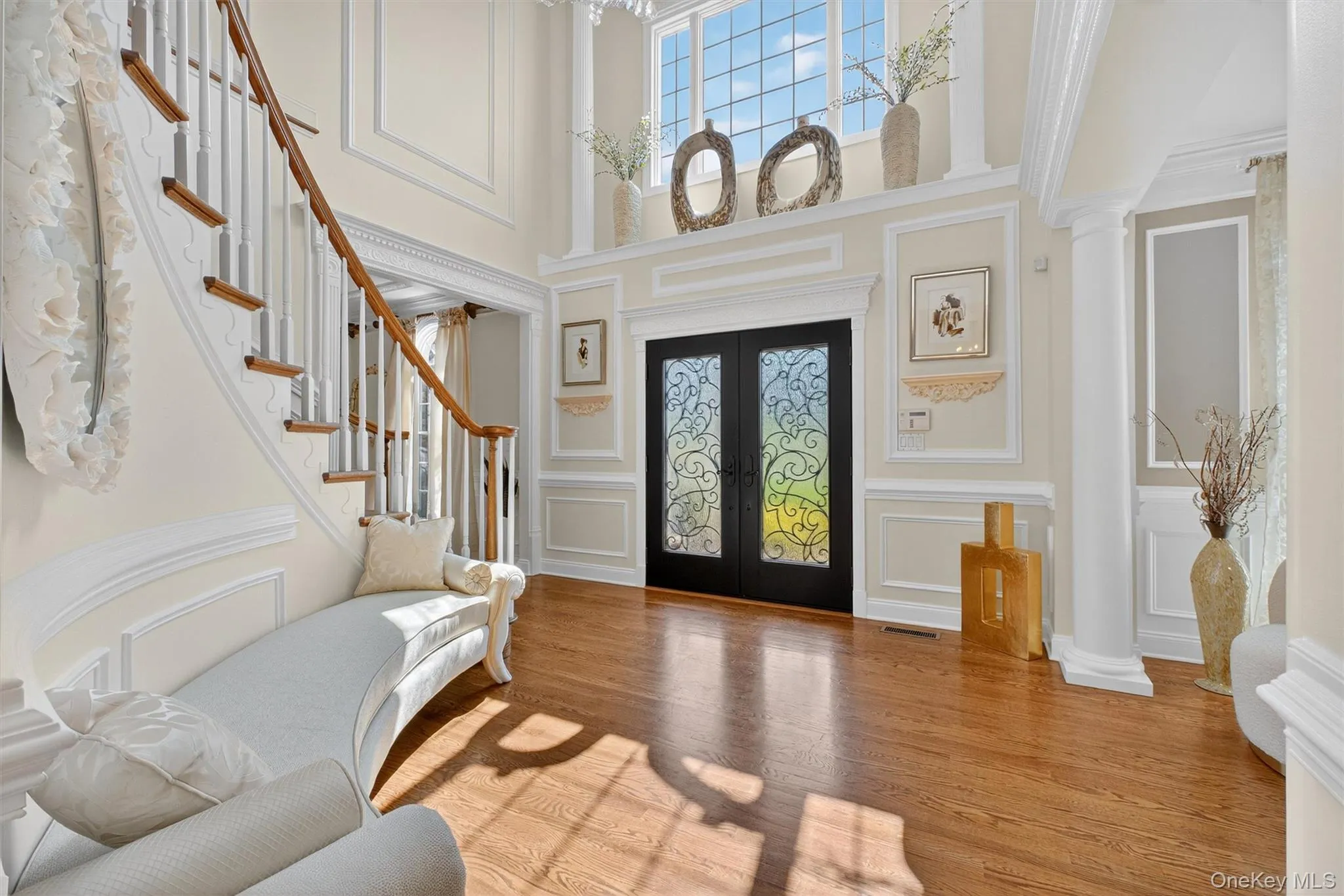 Imagine a breathtaking entryway that immediately sets the tone for the entire home. The light pours in from tall windows, illuminating a soaring two-story foyer where a magnificent chandelier cascades brilliance over gleaming hardwood floors. Dual staircases, gracefully curving on either side, frame the space with symmetry and sophistication. The walls are adorned with fresh, neutral paint, highlighted by intricate wall panels and rich crown molding that exude timeless elegance. Integrated speakers hint at modern comforts, while a state-of-the-art security system offers peace of mind Imagine a breathtaking entryway that immediately sets the tone for the entire home. The light pours in from tall windows, illuminating a soaring two-story foyer where a magnificent chandelier cascades brilliance over gleaming hardwood floors. Dual staircases, gracefully curving on either side, frame the space with symmetry and sophistication. The walls are adorned with fresh, neutral paint, highlighted by intricate wall panels and rich crown molding that exude timeless elegance. Integrated speakers hint at modern comforts, while a state-of-the-art security system offers peace of mind