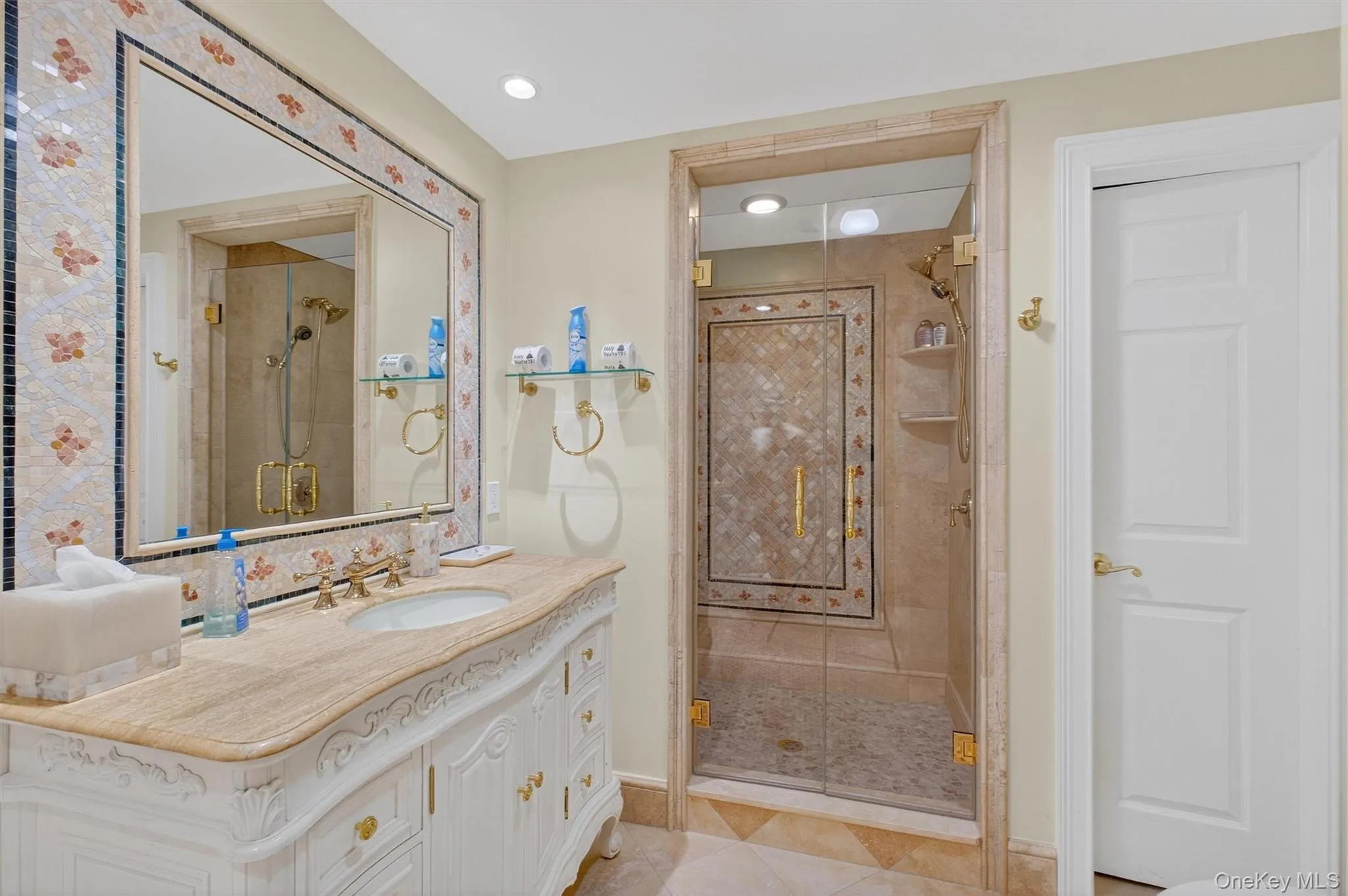 This full-sized bathroom is a true work of art, blending functionality with exquisite design. A furniture-style double vanity with custom moldings, under-mount sinks, and a gleaming quartz top sets the tone, accented by elegant gold faucets. Above, an oversized mirror framed in mosaic glass tile with a butterfly-inspired design becomes a breathtaking focal point, elevating the room into a gallery-worthy space. The massive walk-in shower continues the artistry, featuring the same butterfly mosaic tile, built-in corner shelving, and luxurious gold fixtures including a premium shower body and handheld. A full linen closet and private toilet add convenience, while bright recessed lighting ensures the room feels open, airy, and inviting. This bathroom seamlessly combines sophistication and comfort, making it as practical as it is beautiful. This full-sized bathroom is a true work of art, blending functionality with exquisite design. A furniture-style double vanity with custom moldings, under-mount sinks, and a gleaming quartz top sets the tone, accented by elegant gold faucets. Above, an oversized mirror framed in mosaic glass tile with a butterfly-inspired design becomes a breathtaking focal point, elevating the room into a gallery-worthy space. The massive walk-in shower continues the artistry, featuring the same butterfly mosaic tile, built-in corner shelving, and luxurious gold fixtures including a premium shower body and handheld. A full linen closet and private toilet add convenience, while bright recessed lighting ensures the room feels open, airy, and inviting. This bathroom seamlessly combines sophistication and comfort, making it as practical as it is beautiful.