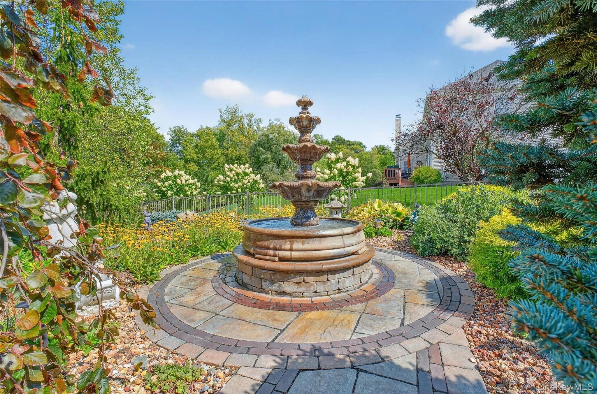Tucked away in a private corner of the grounds, this enchanting retreat is centered around a four-tiered, hand-crafted water feature, a freestanding fountain that brings movement and serenity to the landscape. A scalloped stone paver walkway, bordered by decorative patterned stone, leads the way, while dramatic lava rocks add natural texture and contrast. Every flower, plant, and tree in this space has been professionally curated to harmonize with the fountain, creating a lush, tranquil atmosphere. As the final touch to this resort-inspired backyard, this secluded garden sanctuary offers a magical place to pause, reflect, and take in the beauty of your own private oasis. Tucked away in a private corner of the grounds, this enchanting retreat is centered around a four-tiered, hand-crafted water feature, a freestanding fountain that brings movement and serenity to the landscape. A scalloped stone paver walkway, bordered by decorative patterned stone, leads the way, while dramatic lava rocks add natural texture and contrast. Every flower, plant, and tree in this space has been professionally curated to harmonize with the fountain, creating a lush, tranquil atmosphere. As the final touch to this resort-inspired backyard, this secluded garden sanctuary offers a magical place to pause, reflect, and take in the beauty of your own private oasis.