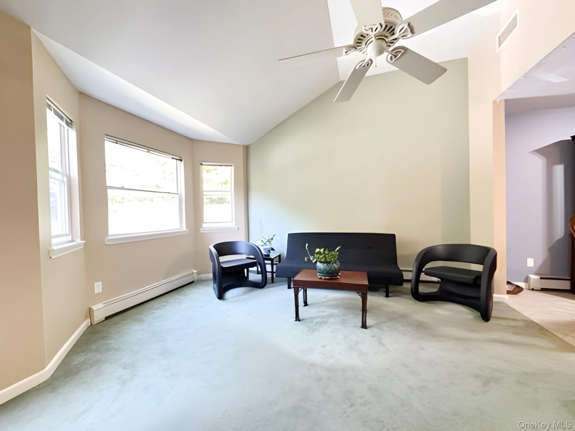 Sitting room featuring a baseboard radiator, carpet, vaulted ceiling, and a ceiling fan Sitting room featuring a baseboard radiator, carpet, vaulted ceiling, and a ceiling fan