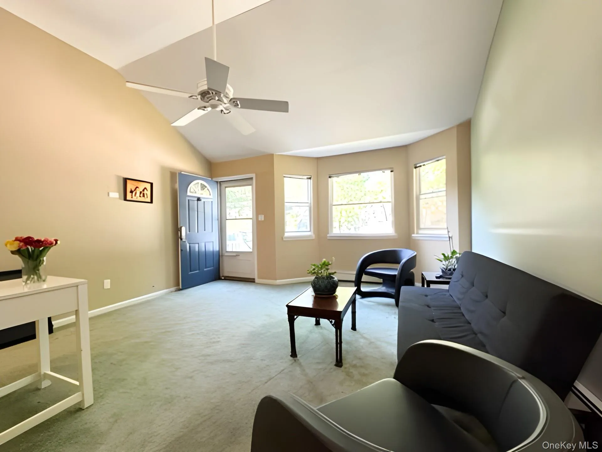 Living area with light colored carpet, ceiling fan, lofted ceiling, and a baseboard radiator Living area with light colored carpet, ceiling fan, lofted ceiling, and a baseboard radiator