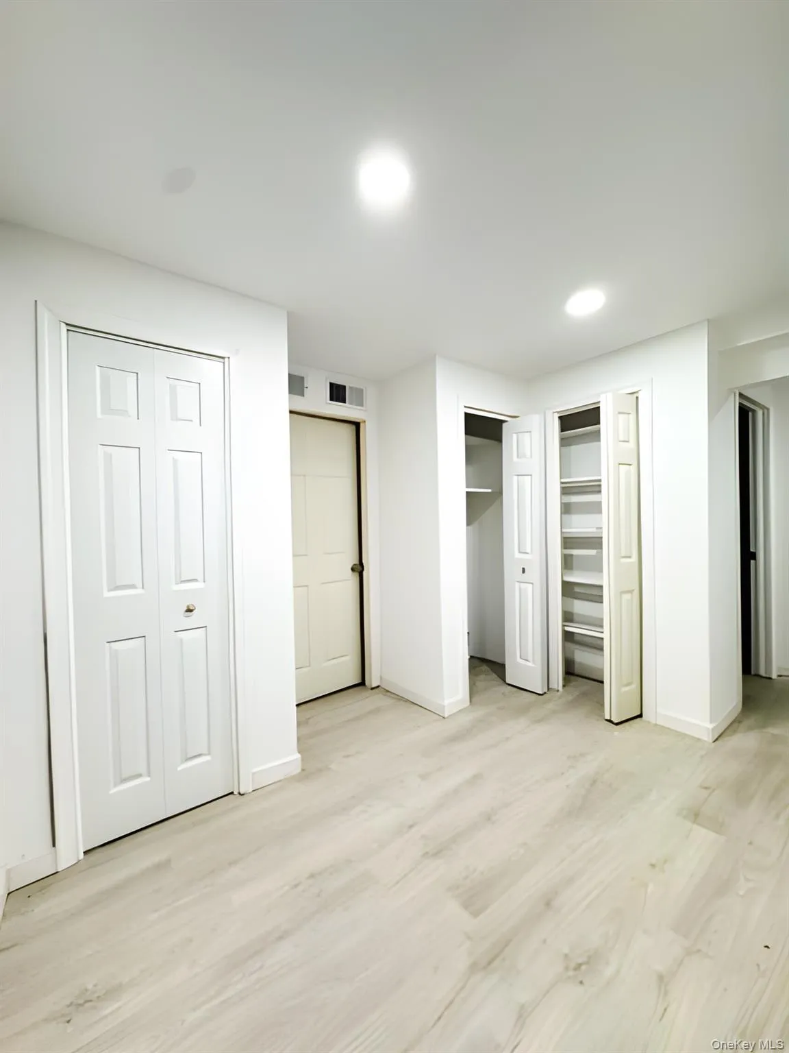 Unfurnished bedroom featuring multiple closets and light wood-type flooring Unfurnished bedroom featuring multiple closets and light wood-type flooring