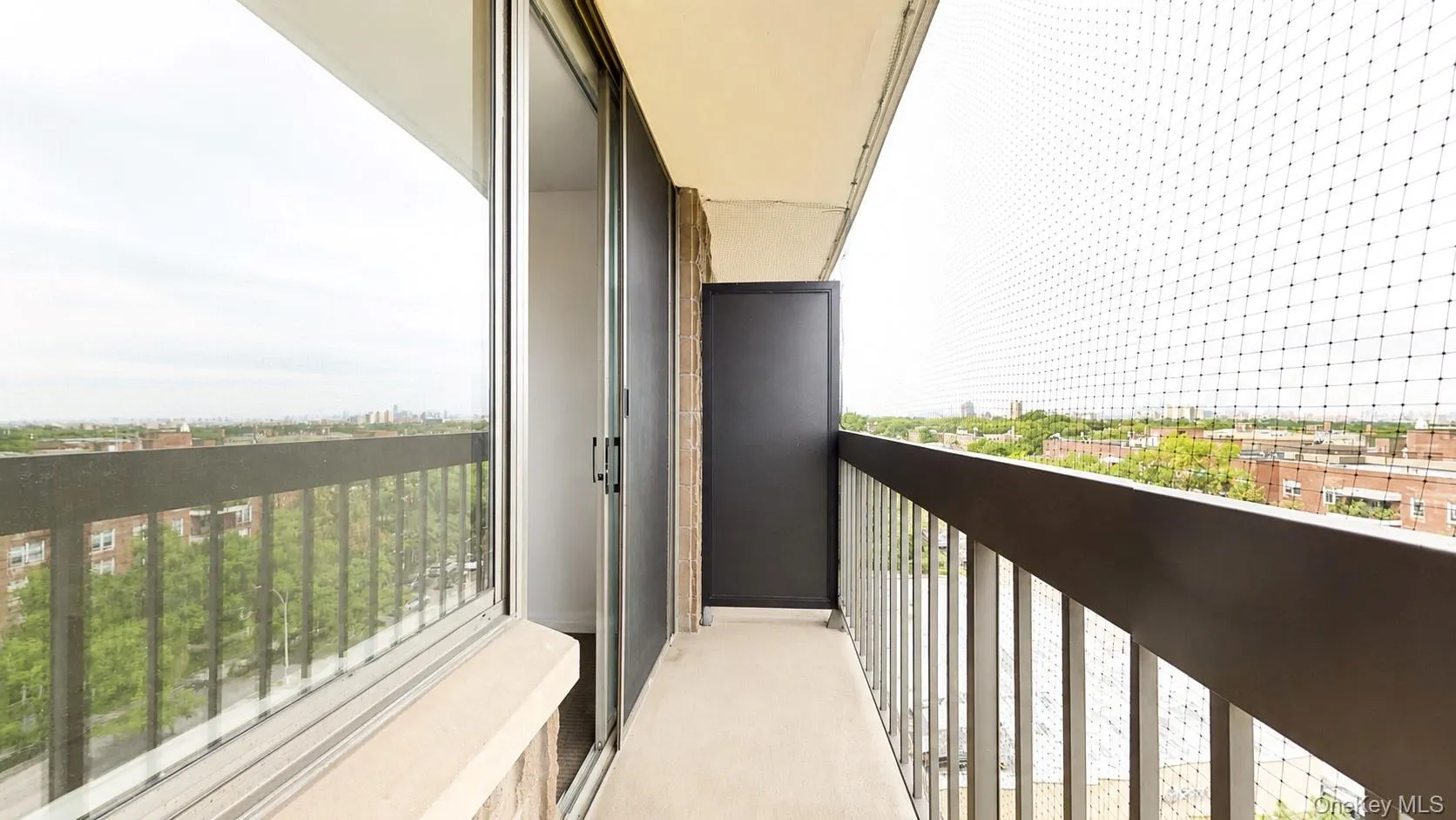 Balcony with sliding glass door, metal railing, and a cityscape backdrop Balcony with sliding glass door, metal railing, and a cityscape backdrop