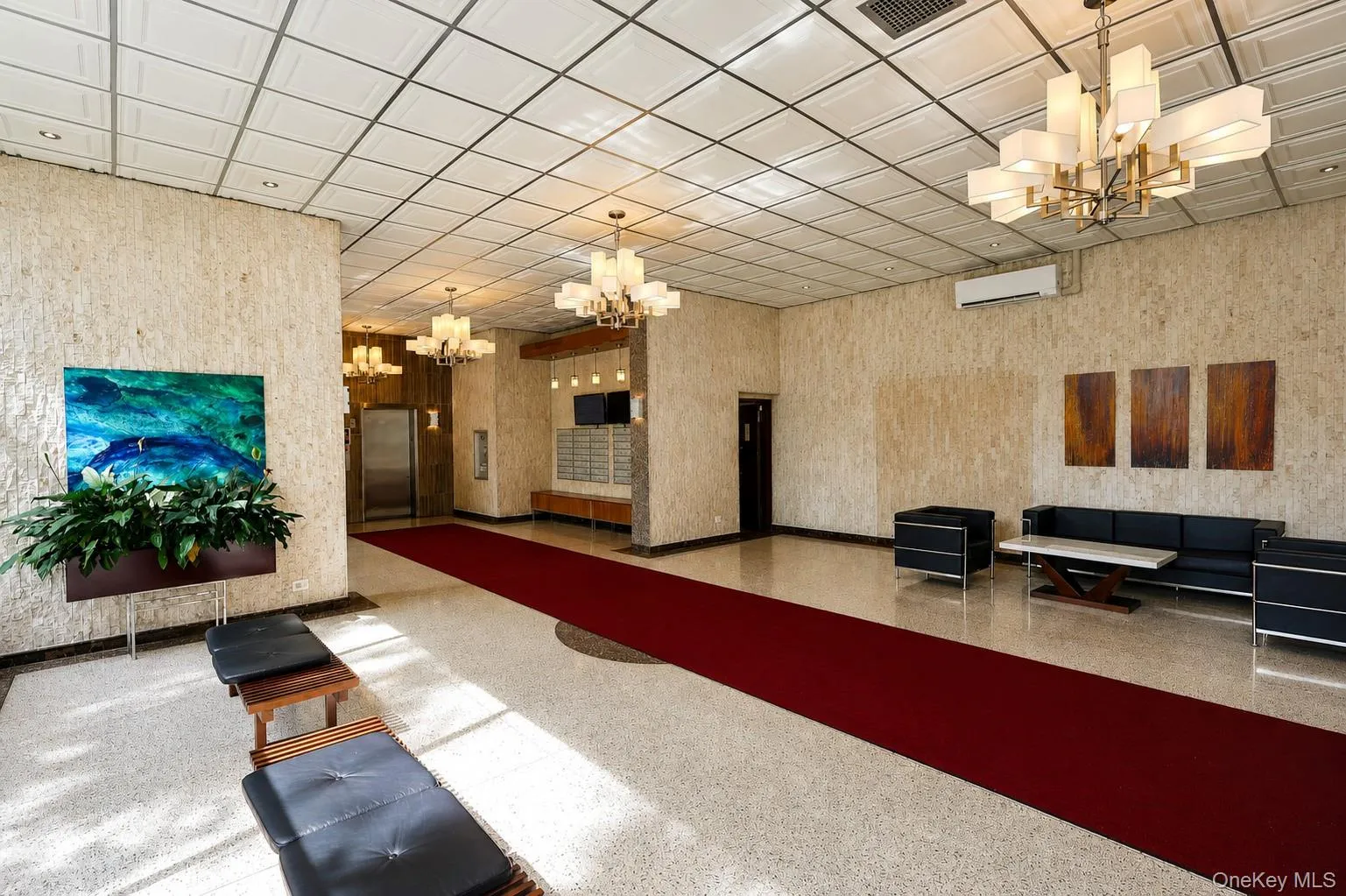 Spacious reception area with textured wall finishes, recessed lighting, and stylish chandeliers Spacious reception area with textured wall finishes, recessed lighting, and stylish chandeliers