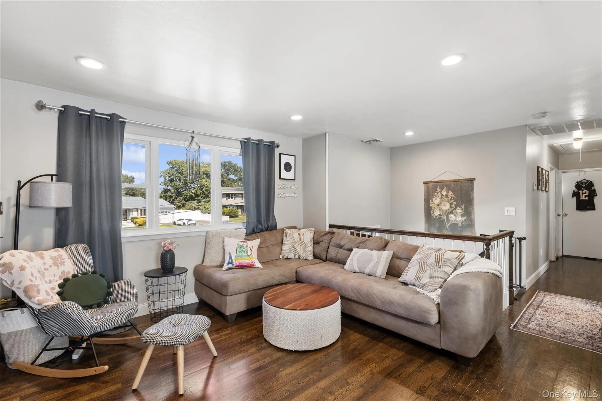 Hardwood flooring, recessed lighting, white window trim, and a wood banister with white spindles Hardwood flooring, recessed lighting, white window trim, and a wood banister with white spindles