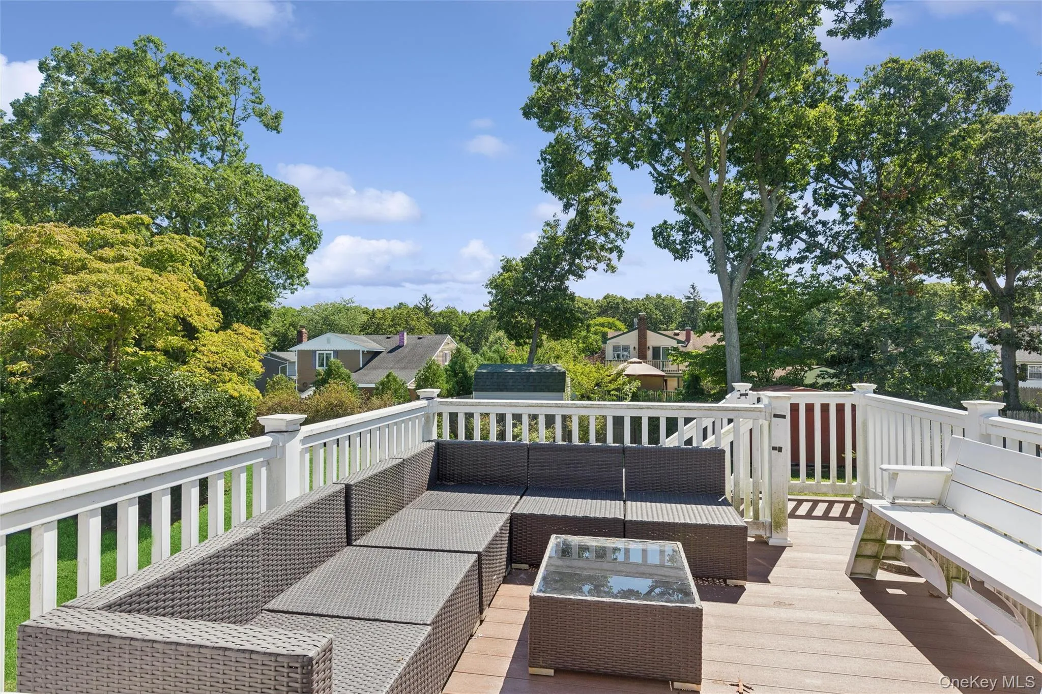 Expansive deck with white railing, composite decking, and surrounding mature trees Expansive deck with white railing, composite decking, and surrounding mature trees