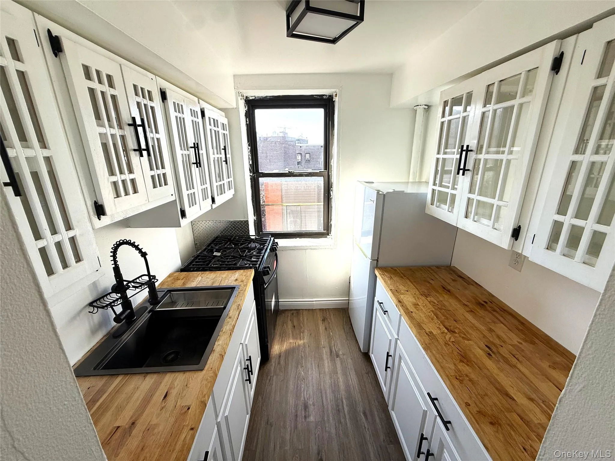 Updated kitchen with wooden counters, glass-paned cabinetry, and appliances. Updated kitchen with wooden counters, glass-paned cabinetry, and appliances.