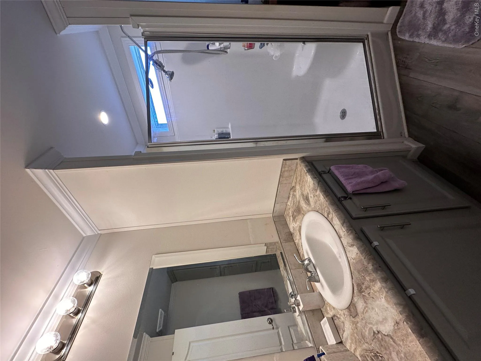 Vanity with oval sink, patterned countertop, and wood-finish flooring. Vanity with oval sink, patterned countertop, and wood-finish flooring.
