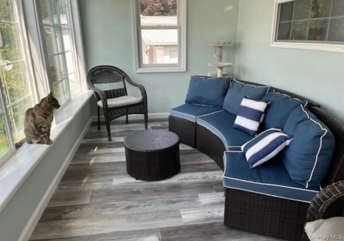 Sunroom featuring multiple windows, wood-finish flooring, and light blue wall tones. Sunroom featuring multiple windows, wood-finish flooring, and light blue wall tones.