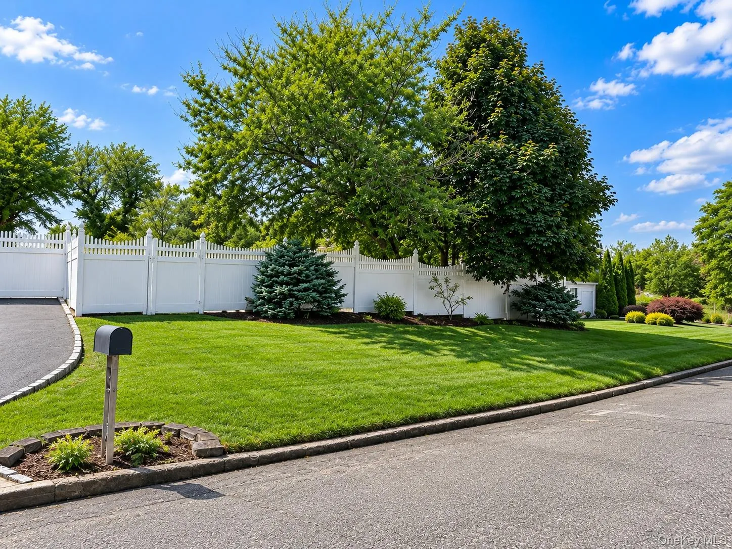 Expansive manicured lawn anchored by mature shade trees and bordered by white vinyl fencing Expansive manicured lawn anchored by mature shade trees and bordered by white vinyl fencing