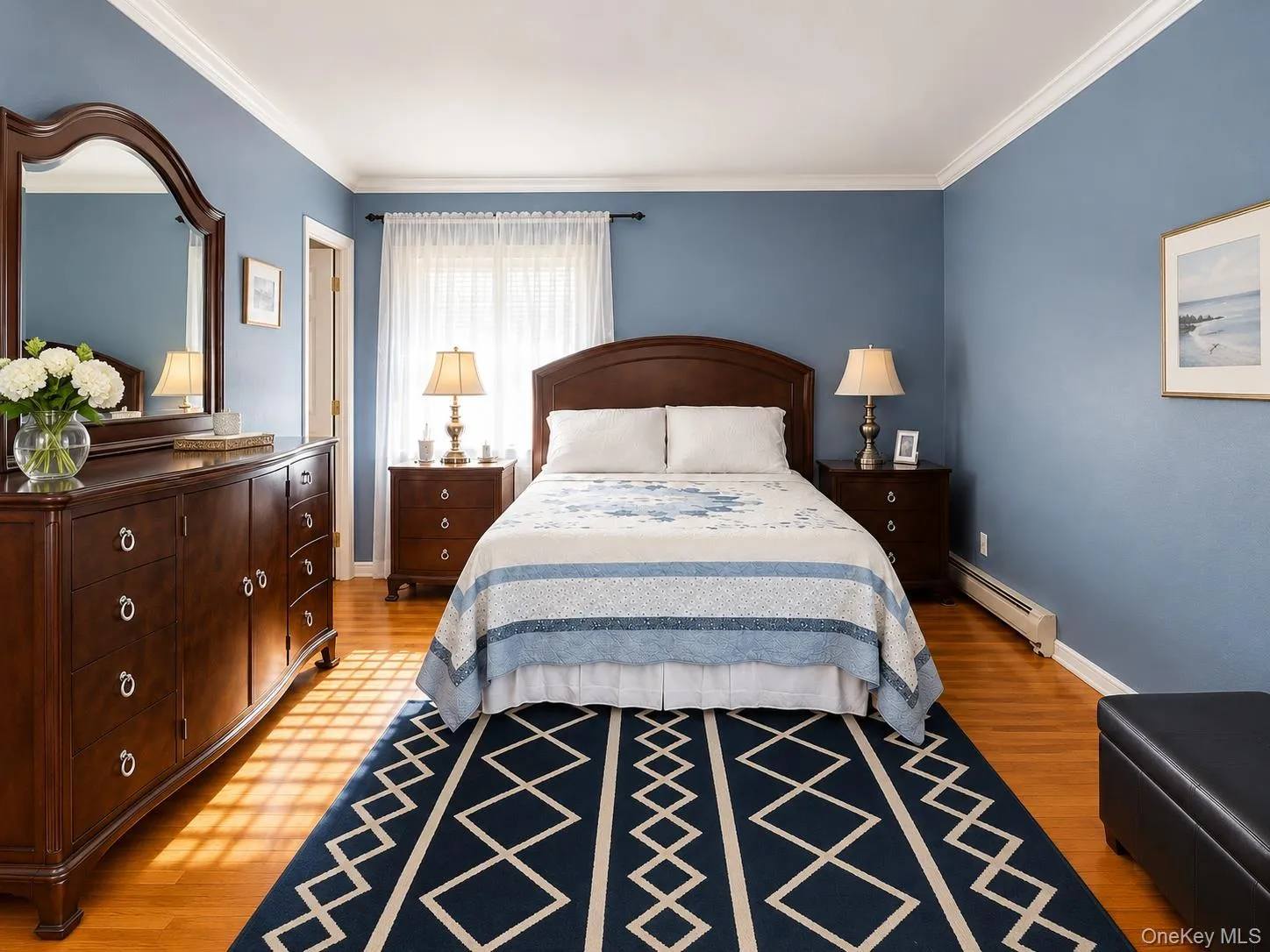 Serene primary bedroom with full bathroom showcasing soft blue walls, hardwood flooring, and crown molding Serene primary bedroom with full bathroom showcasing soft blue walls, hardwood flooring, and crown molding