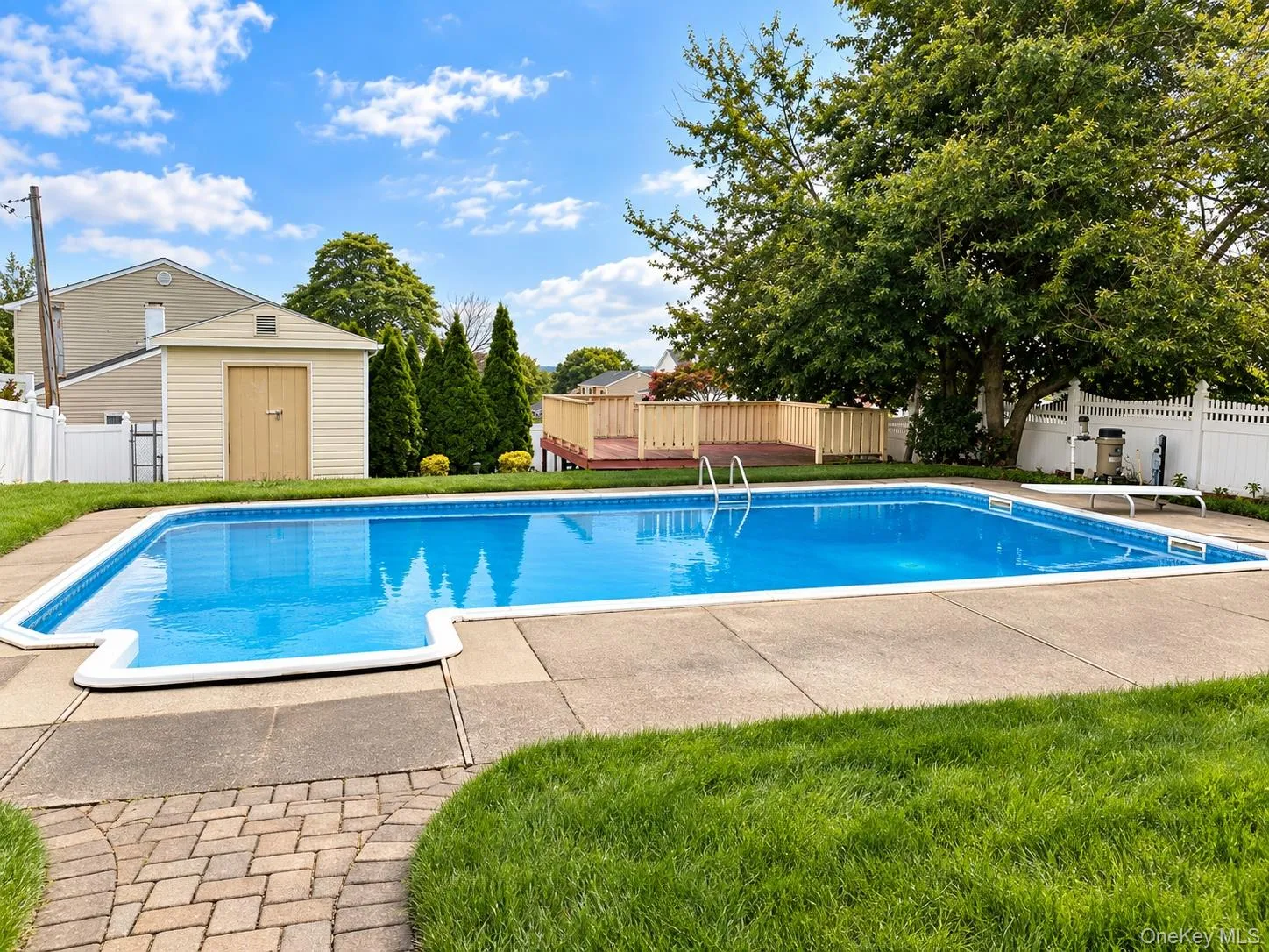 In-ground swimming pool with surrounding concrete patio, paver walkway, and privacy fencing In-ground swimming pool with surrounding concrete patio, paver walkway, and privacy fencing