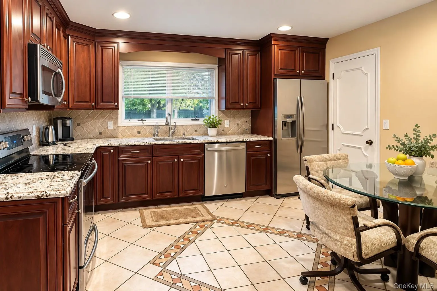 Cherry-finish cabinetry, stainless steel appliances, granite countertops, and tiled flooring with an inlaid pattern Cherry-finish cabinetry, stainless steel appliances, granite countertops, and tiled flooring with an inlaid pattern