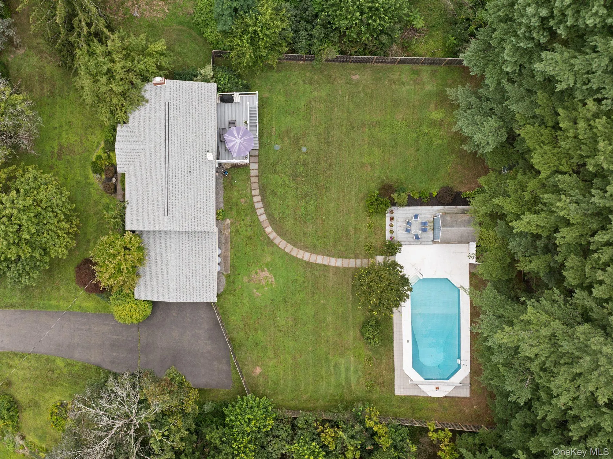 Expansive green lot featuring a residential structure, paved driveway, and an in-ground swimming pool Expansive green lot featuring a residential structure, paved driveway, and an in-ground swimming pool