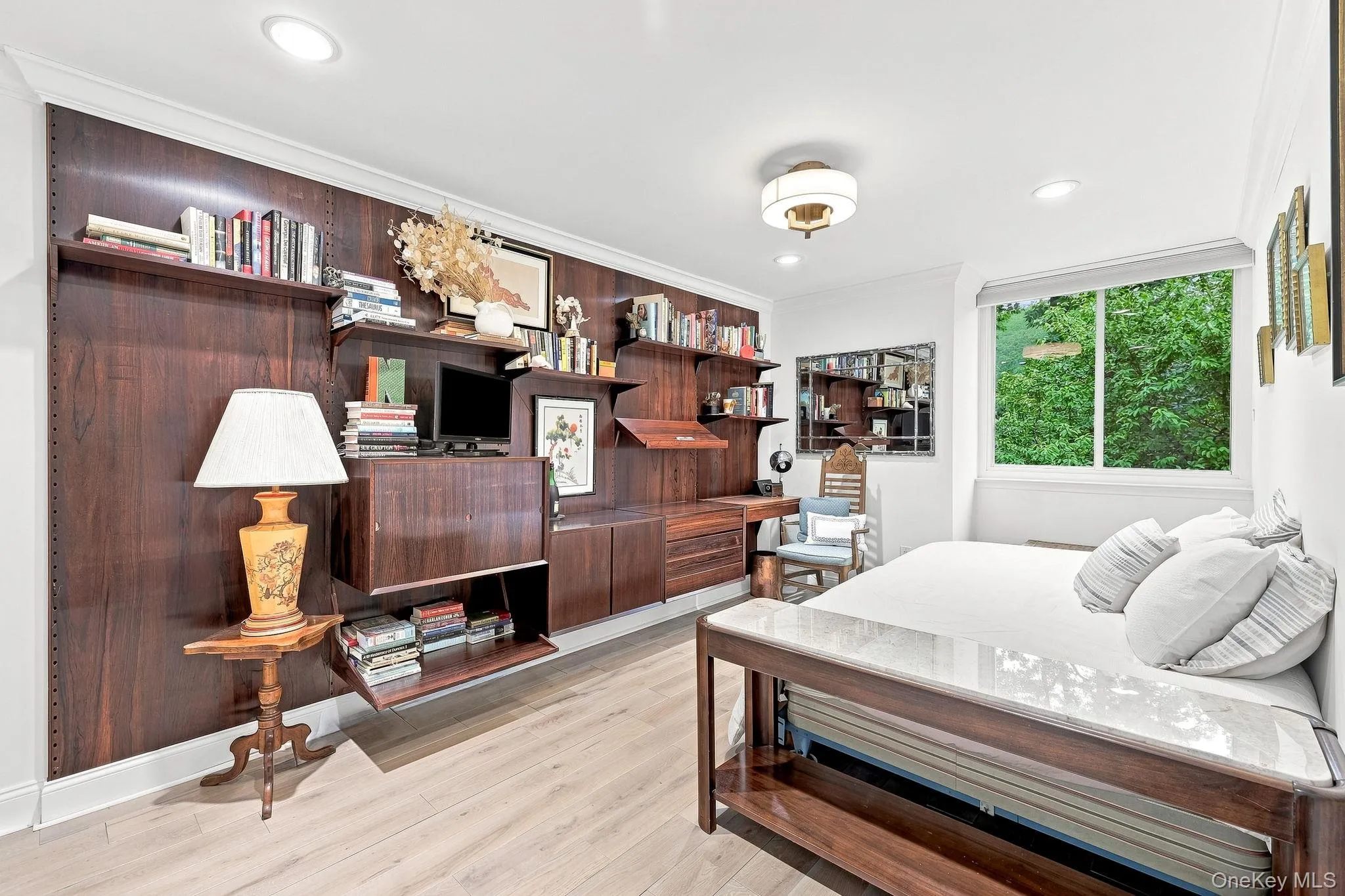 The second bedroom has a wall of built-in cabinetry and shelving and a window with a Hunter Douglas shade The second bedroom has a wall of built-in cabinetry and shelving and a window with a Hunter Douglas shade