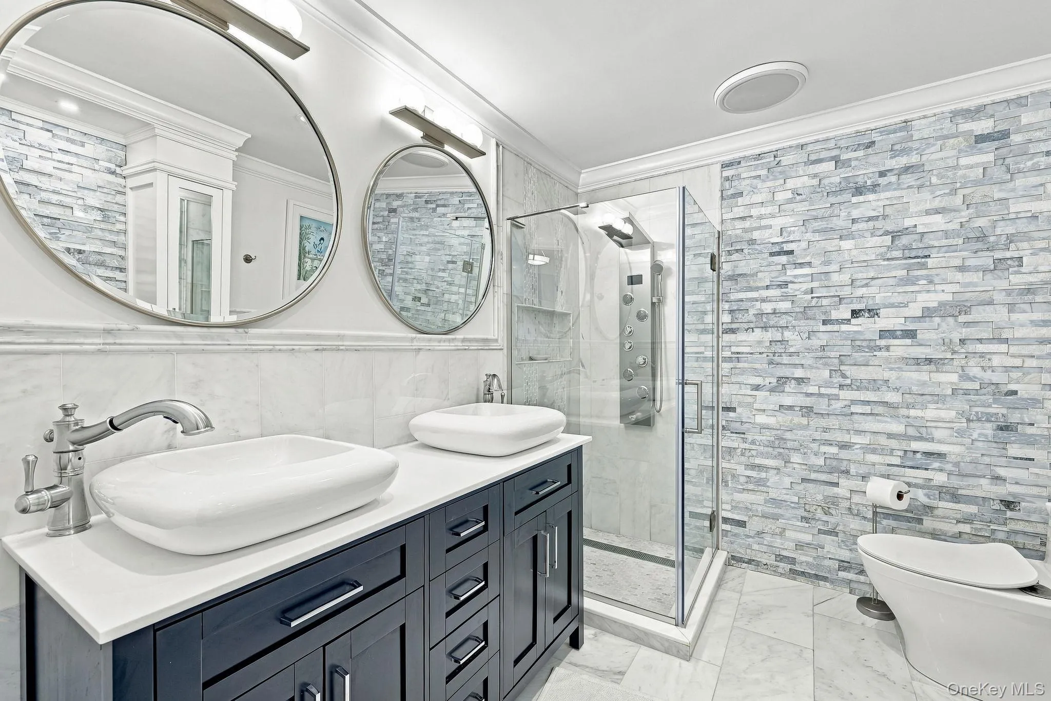 White Greek Thassos marble countertop on the vanity with vessel-style double sinks in this primary bathroom White Greek Thassos marble countertop on the vanity with vessel-style double sinks in this primary bathroom