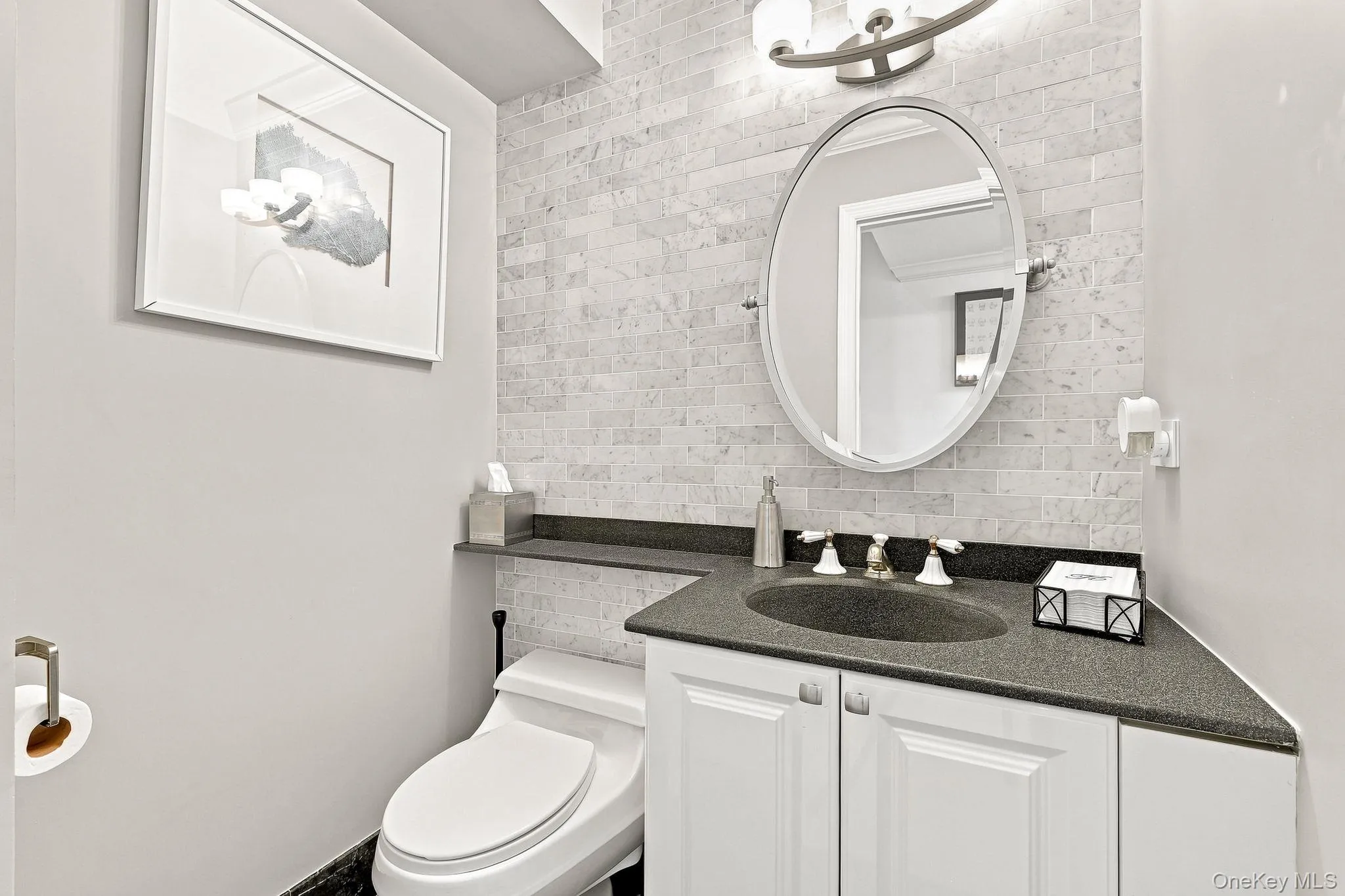 Powder room on the first floor has black marble flooring and marble subway tile on the walls Powder room on the first floor has black marble flooring and marble subway tile on the walls