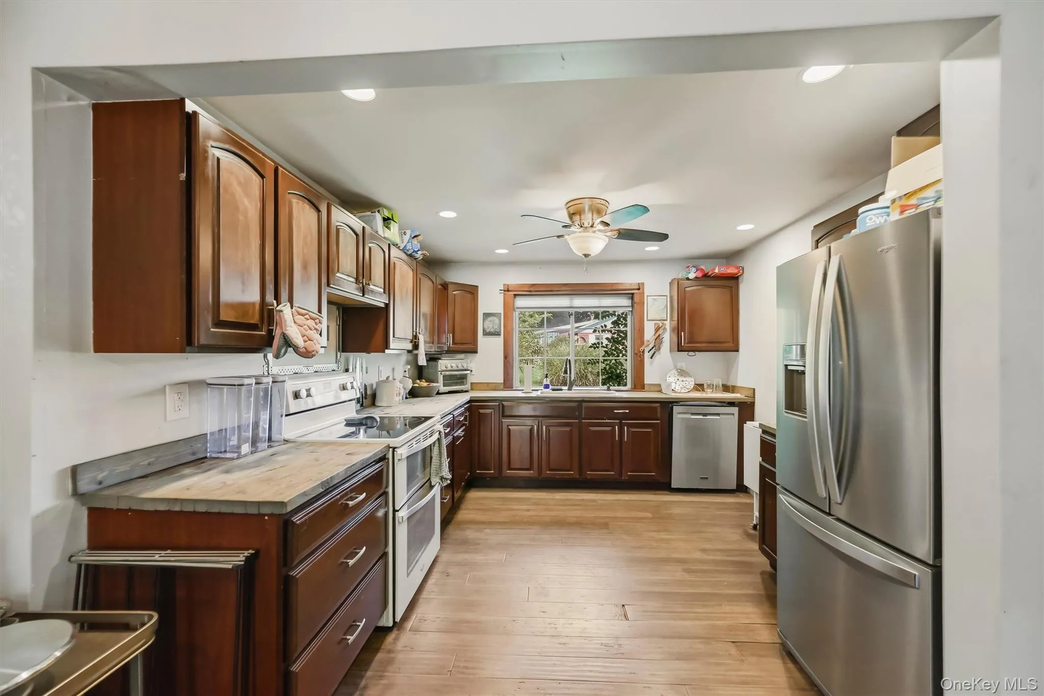 Kitchen featuring wood-finish flooring, recessed lighting, wood cabinetry, stainless steel appliances, custom wooden countertops, and a window above the sink Kitchen featuring wood-finish flooring, recessed lighting, wood cabinetry, stainless steel appliances, custom wooden countertops, and a window above the sink