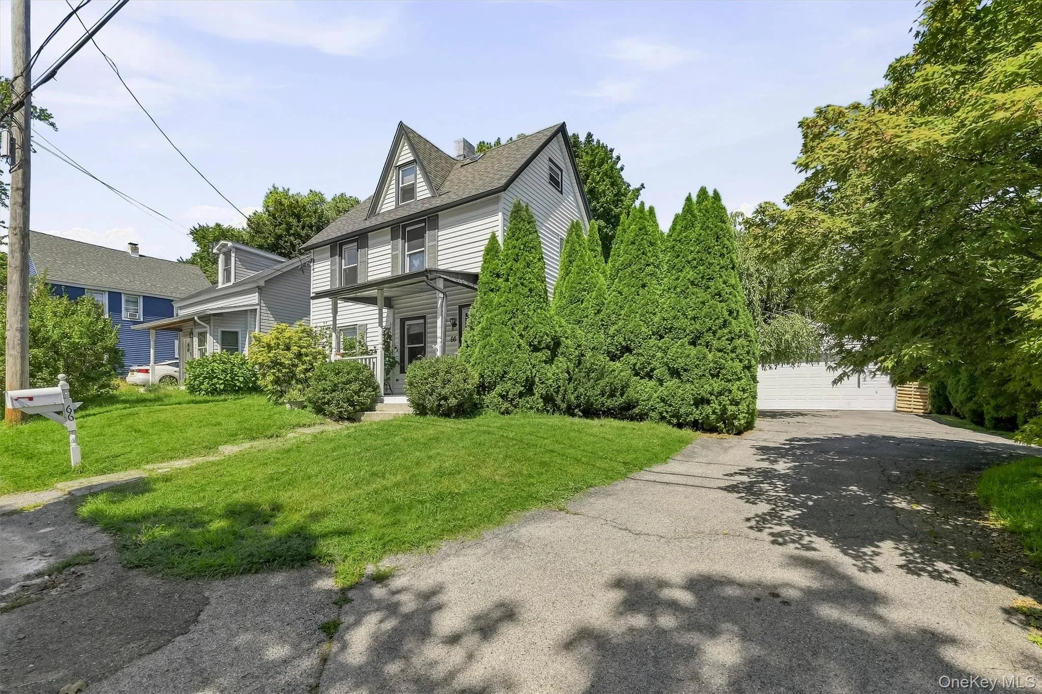 Siding exterior with a covered front porch, dormer window, established front lawn, mature shrubs, and an asphalt driveway Siding exterior with a covered front porch, dormer window, established front lawn, mature shrubs, and an asphalt driveway