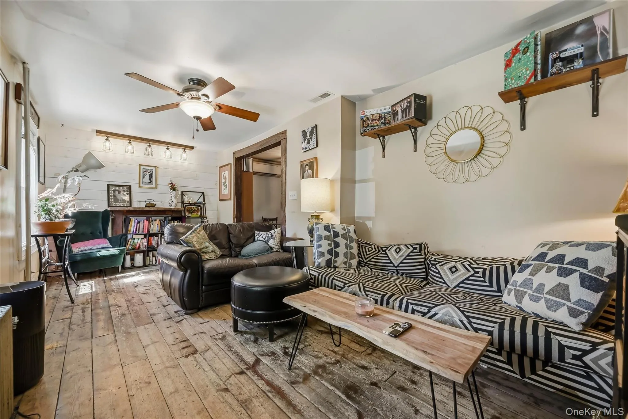 Distressed wood-finish flooring, ceiling fan with integrated lighting, built-in wooden shelving, and a track lighting fixture with multiple bulbs Distressed wood-finish flooring, ceiling fan with integrated lighting, built-in wooden shelving, and a track lighting fixture with multiple bulbs
