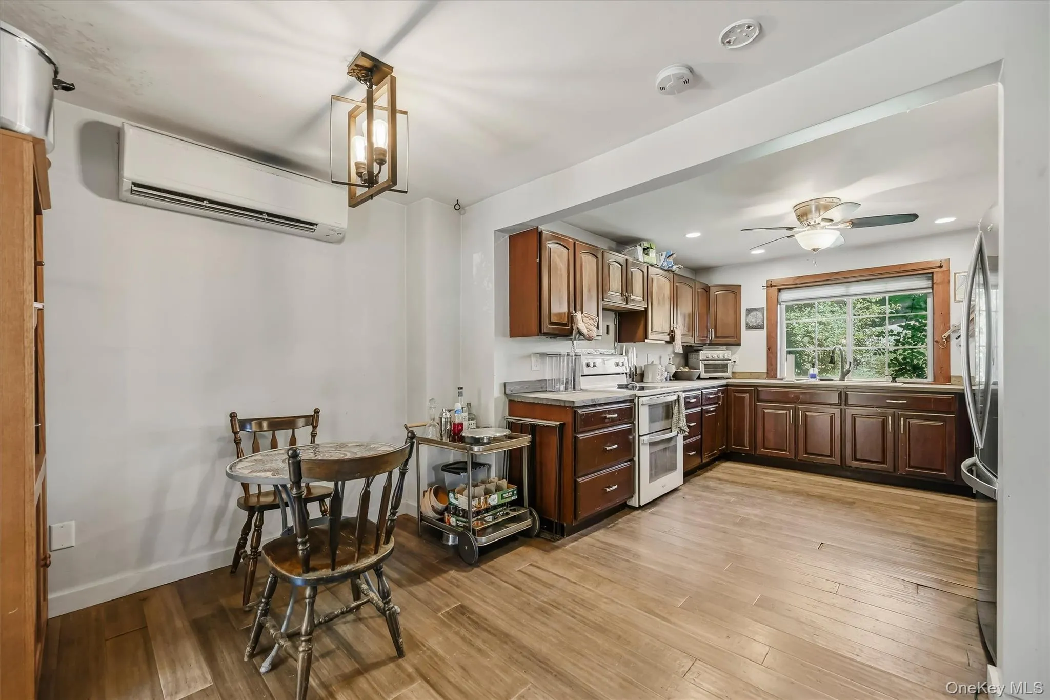 Kitchen featuring wood-finish flooring, recessed lighting, wood cabinetry, split unit, and a ceiling fan Kitchen featuring wood-finish flooring, recessed lighting, wood cabinetry, split unit, and a ceiling fan