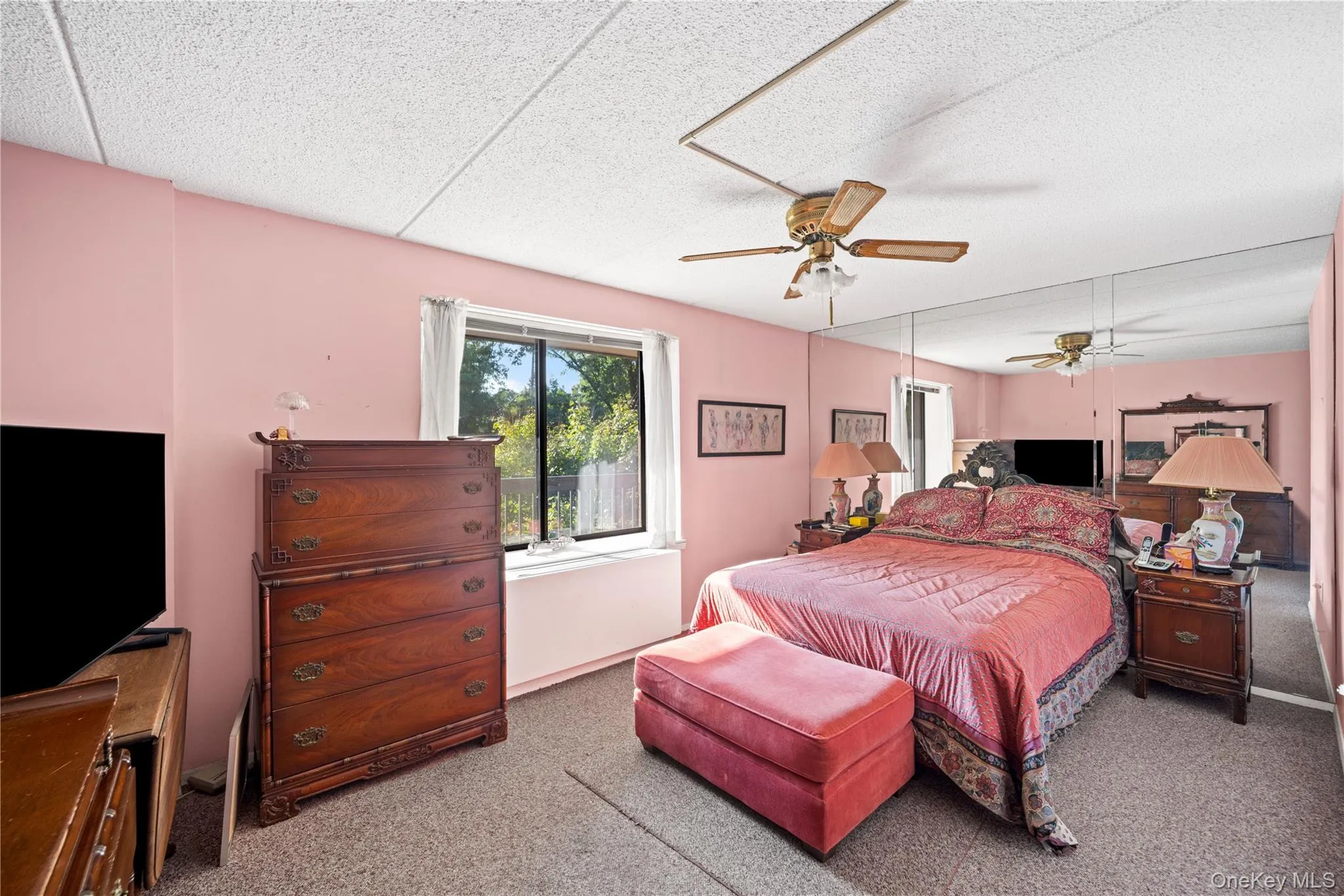 Window with outdoor scenery, full wall mirror, and ceiling fan Window with outdoor scenery, full wall mirror, and ceiling fan