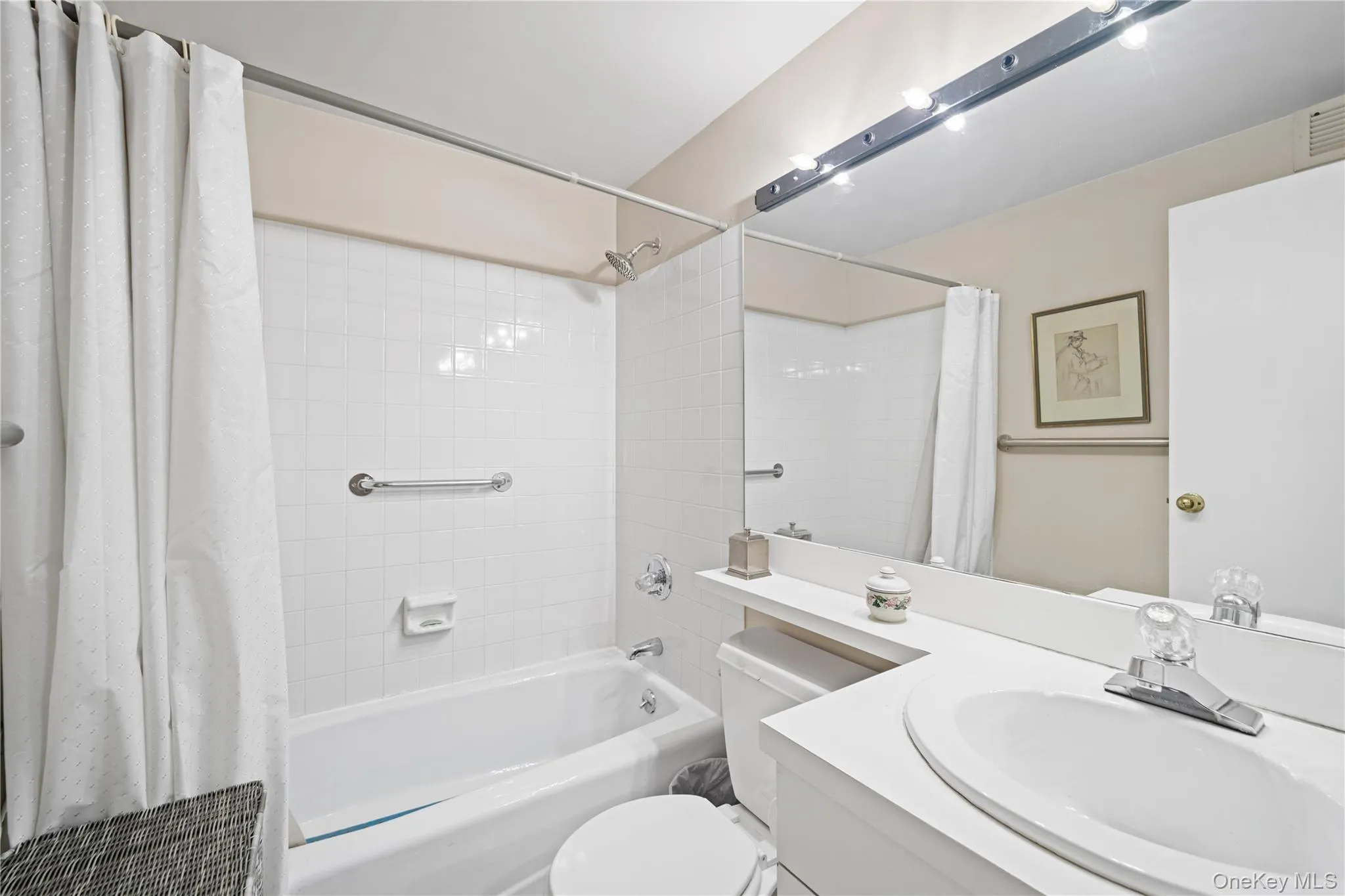 White tile tub surround, chrome grab bars, and shower fixtures White tile tub surround, chrome grab bars, and shower fixtures