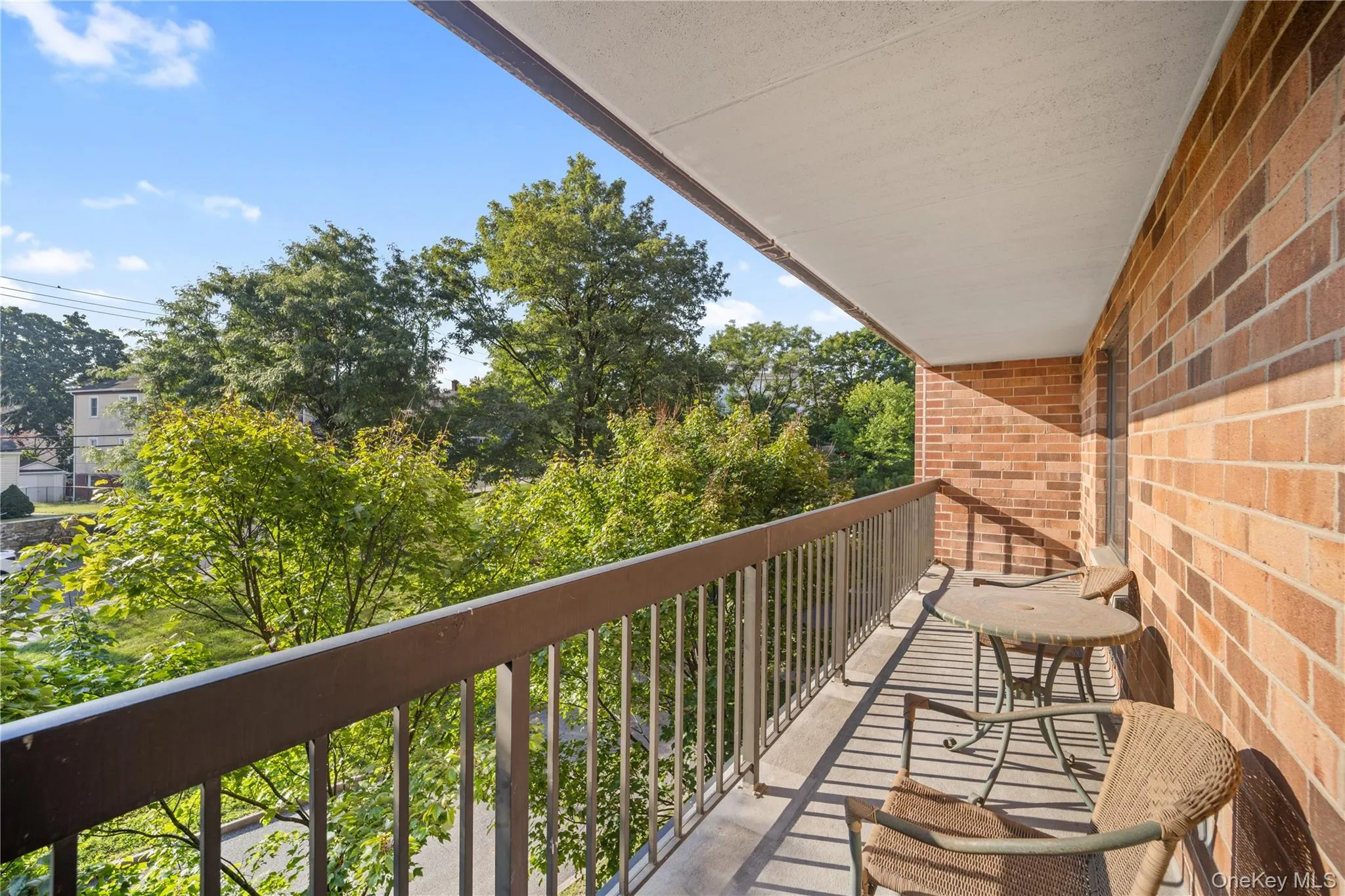 Exterior balcony featuring a brick wall, metal railing, and an overhead awning Exterior balcony featuring a brick wall, metal railing, and an overhead awning