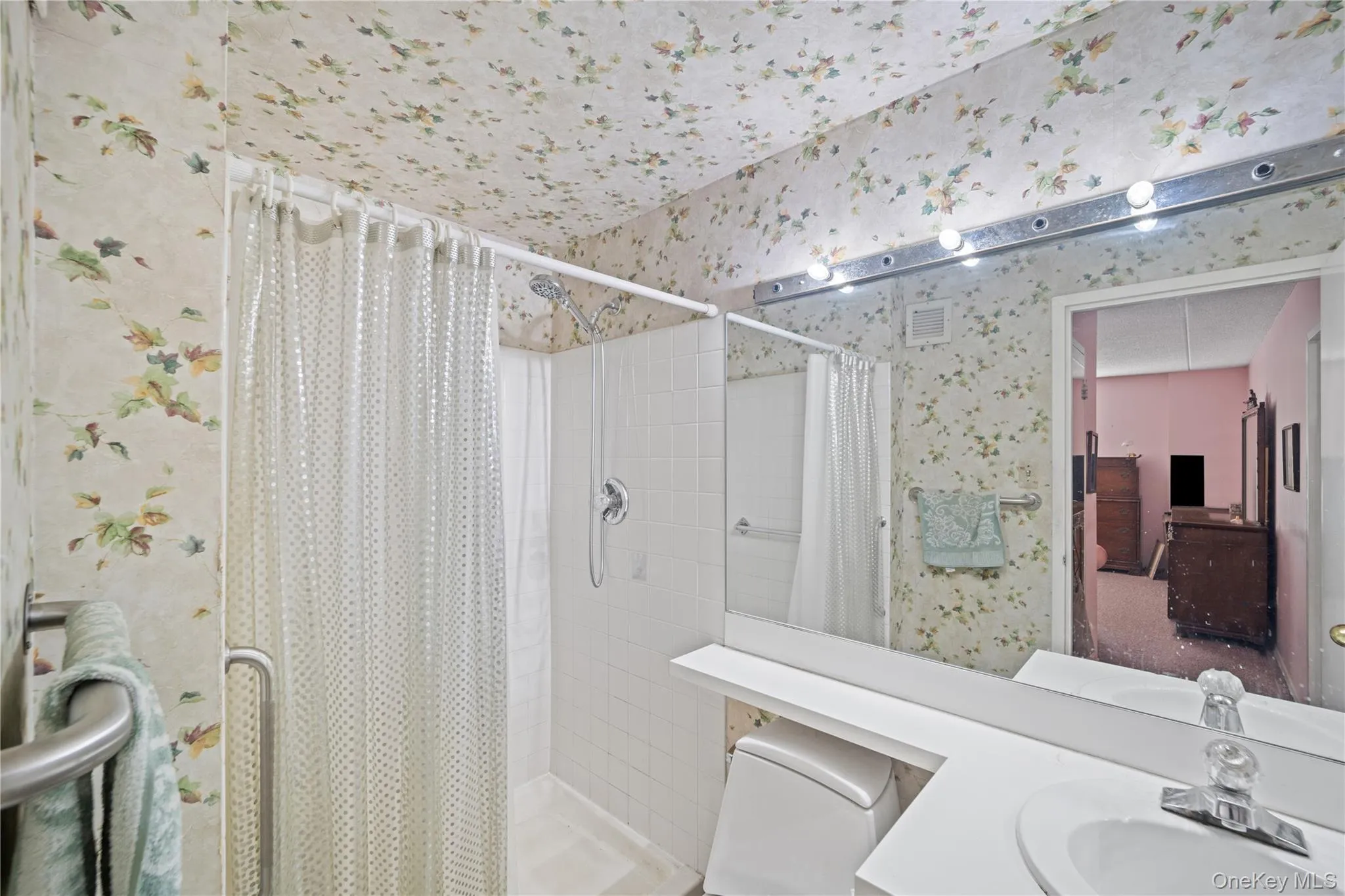 Shower stall with white tile surround and grab bar Shower stall with white tile surround and grab bar