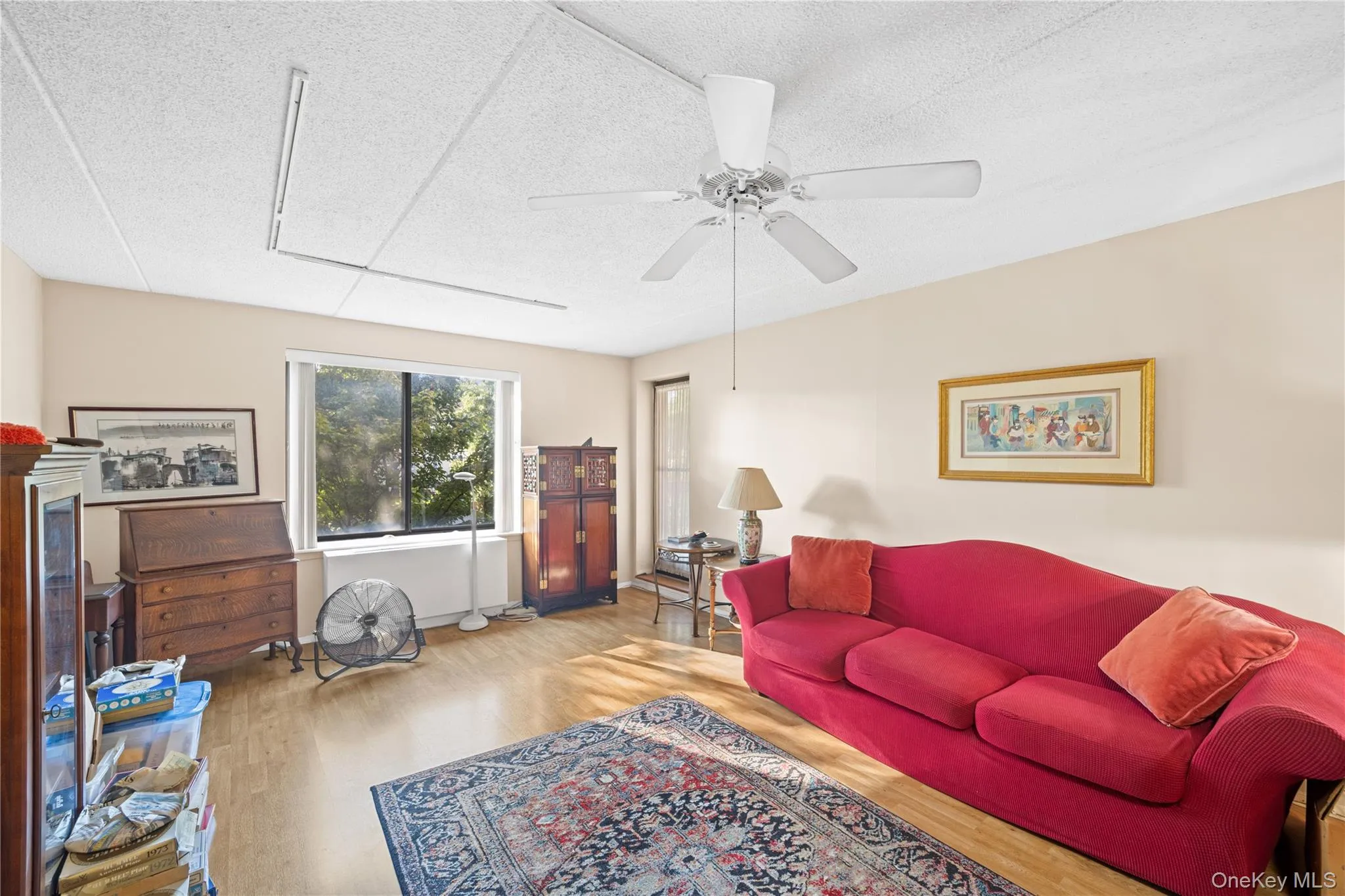Wood-finish flooring throughout, ceiling fan with integrated lighting, and a large window providing ample natural light Wood-finish flooring throughout, ceiling fan with integrated lighting, and a large window providing ample natural light