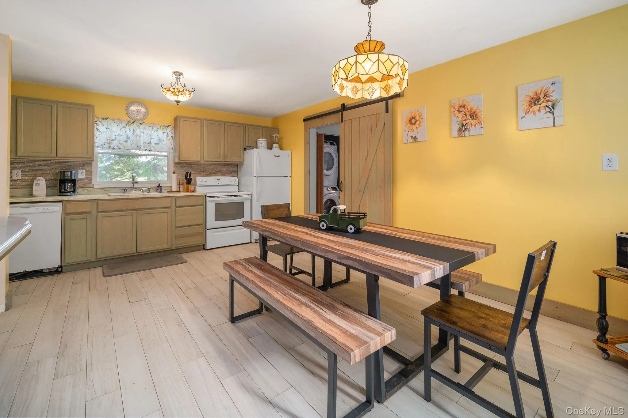 Kitchen featuring light wood-finish flooring, white appliances, and a tiled backsplash Kitchen featuring light wood-finish flooring, white appliances, and a tiled backsplash