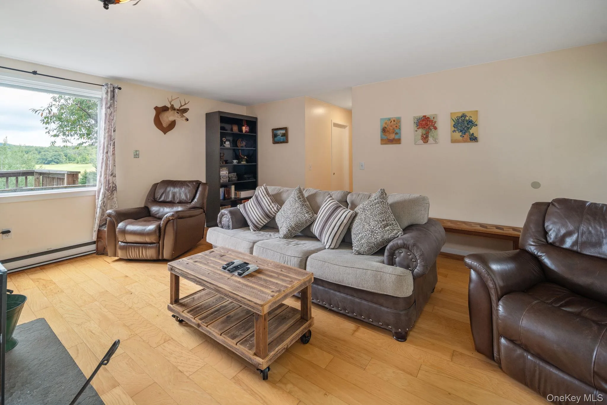 Hardwood flooring, expansive window, built-in shelving, light-toned walls, and ceiling-mounted lighting Hardwood flooring, expansive window, built-in shelving, light-toned walls, and ceiling-mounted lighting