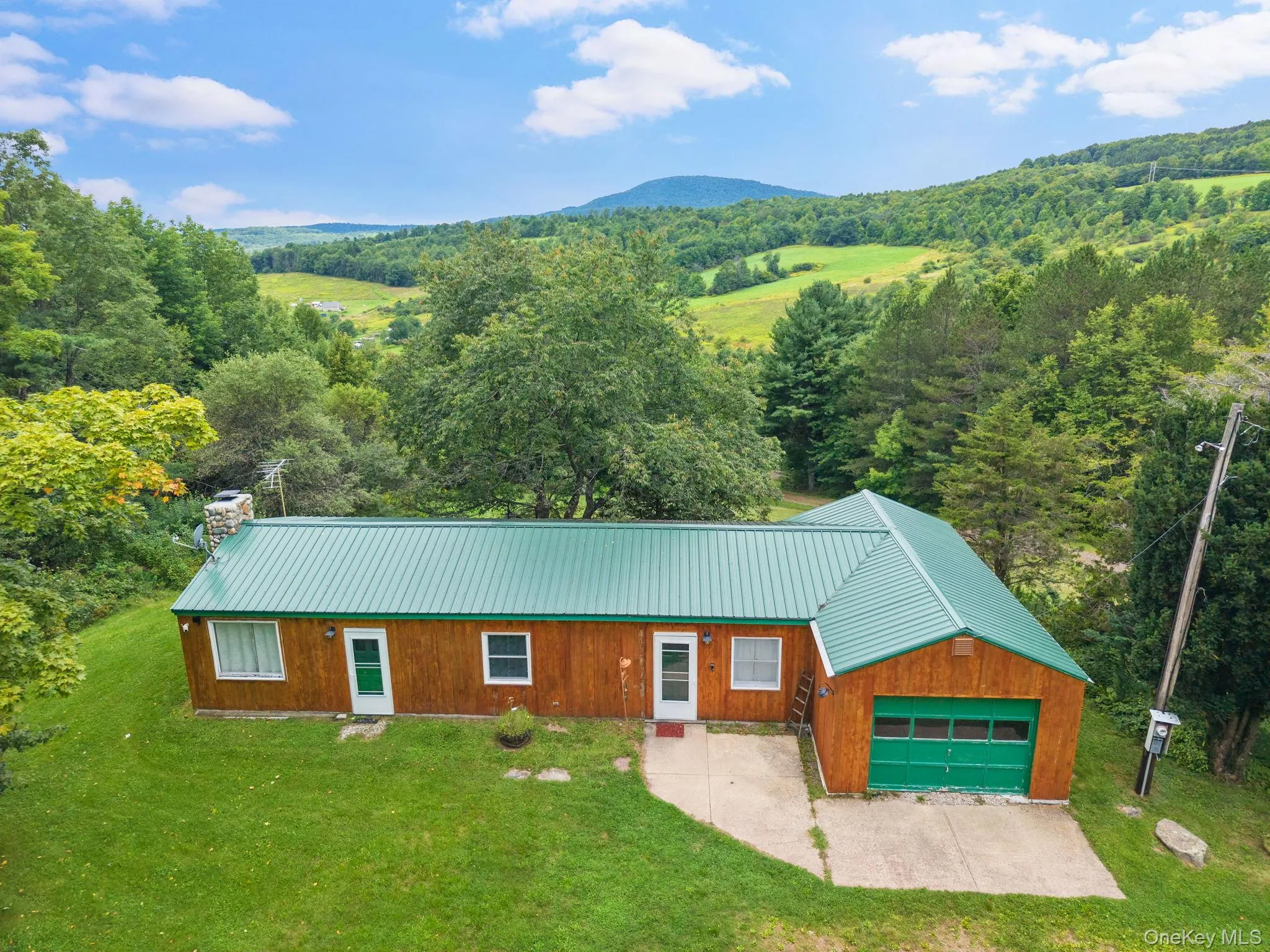 Wood-sided residence with a green metal roof and an attached garage Wood-sided residence with a green metal roof and an attached garage