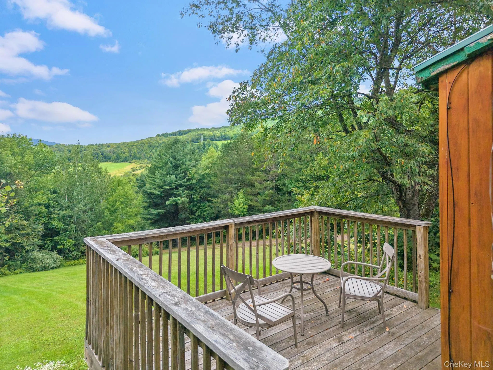 Wood deck with railing overlooking a landscape of mature trees and distant hills Wood deck with railing overlooking a landscape of mature trees and distant hills