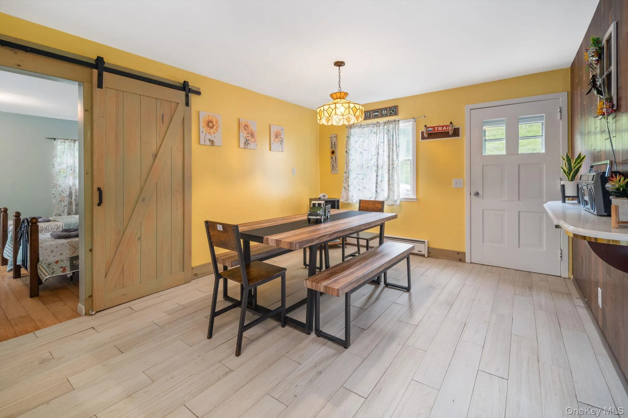 Light wood-finish plank flooring, wood barn door, and a white paneled door with glass inserts Light wood-finish plank flooring, wood barn door, and a white paneled door with glass inserts