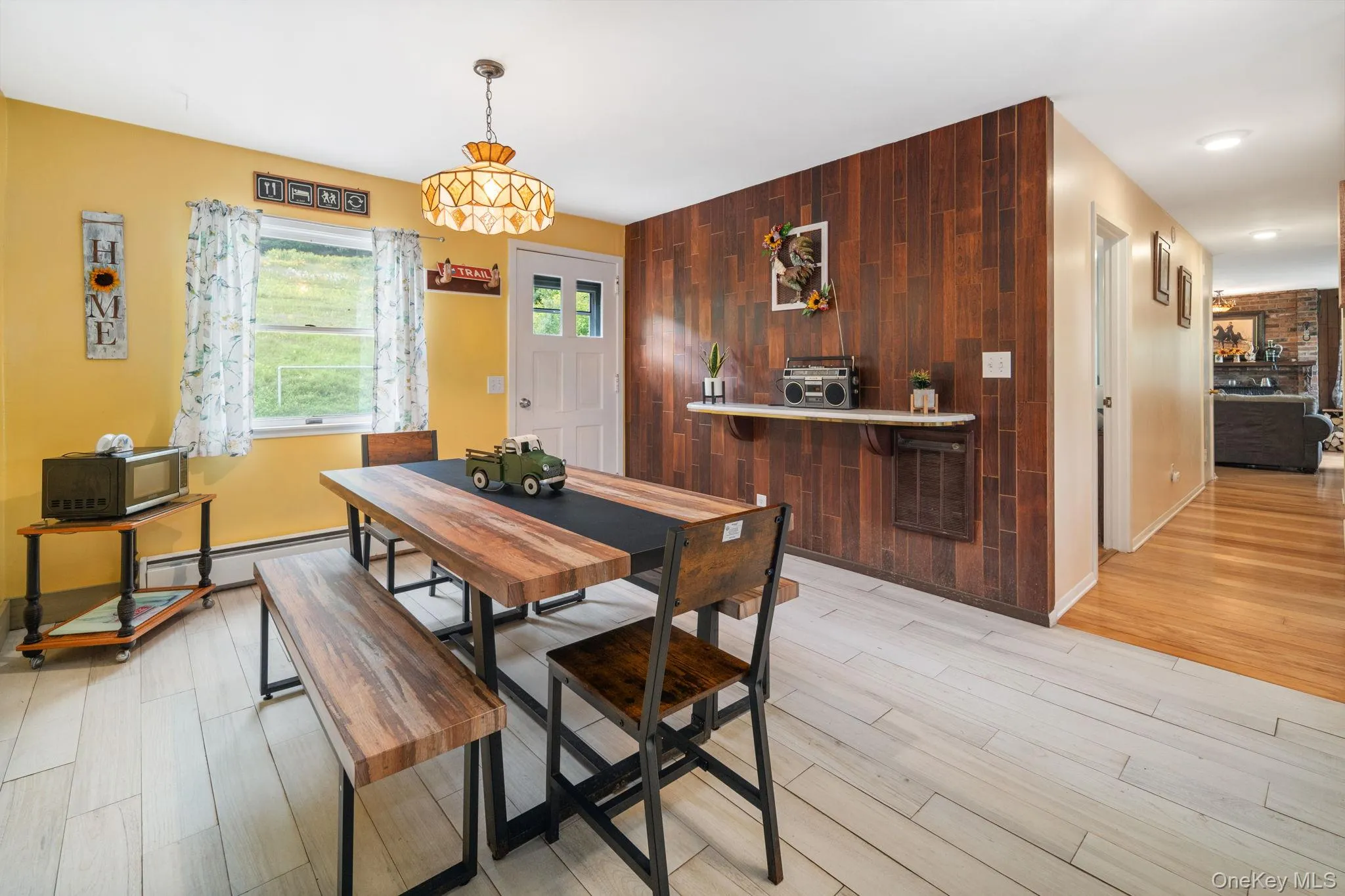 Wood-finish accent wall with a built-in floating shelf, light wood-finish flooring, and a decorative ceiling fixture Wood-finish accent wall with a built-in floating shelf, light wood-finish flooring, and a decorative ceiling fixture
