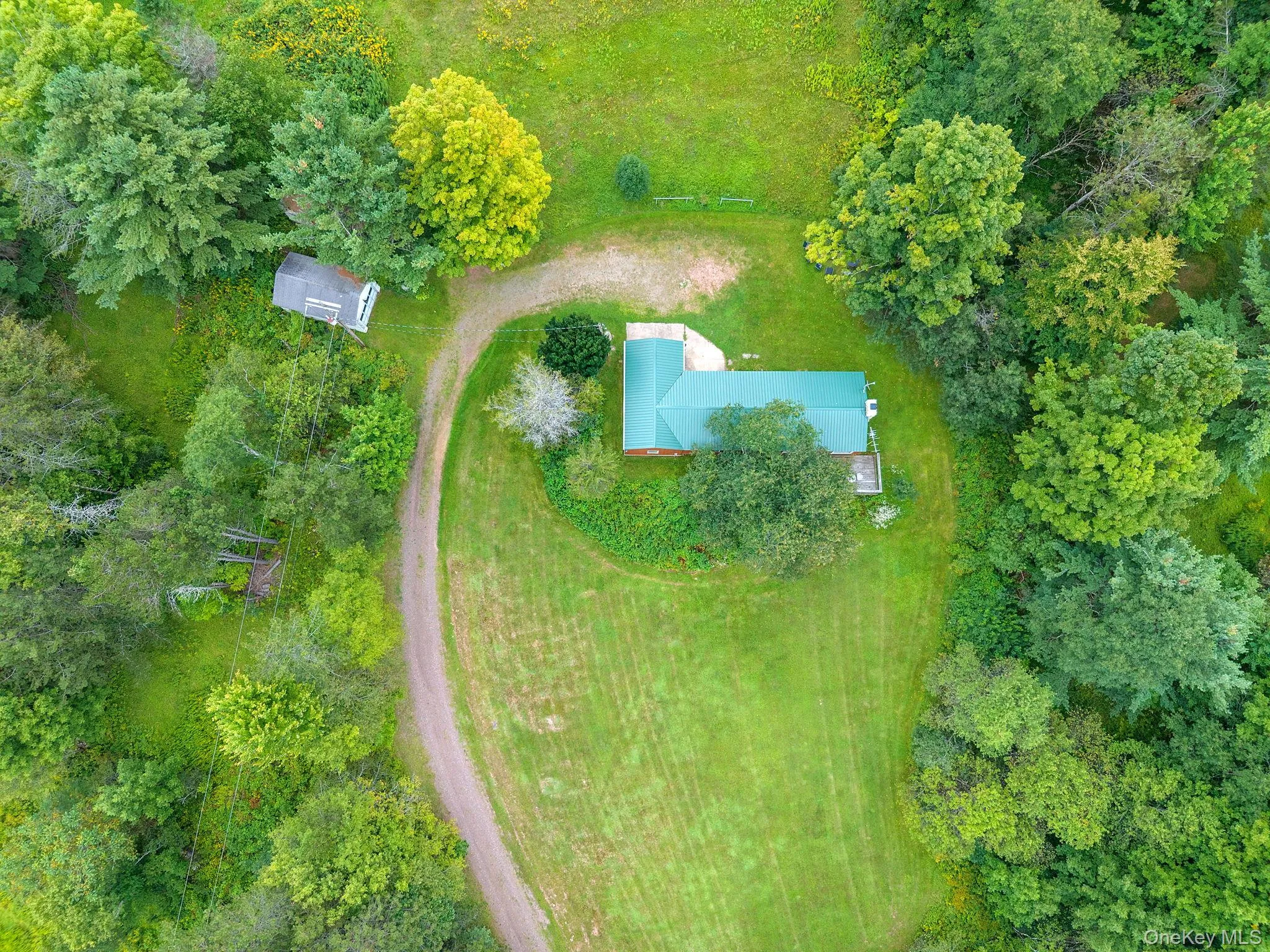 Expansive natural landscape with a gravel drive, a structure with a green roof, and a separate outbuilding Expansive natural landscape with a gravel drive, a structure with a green roof, and a separate outbuilding
