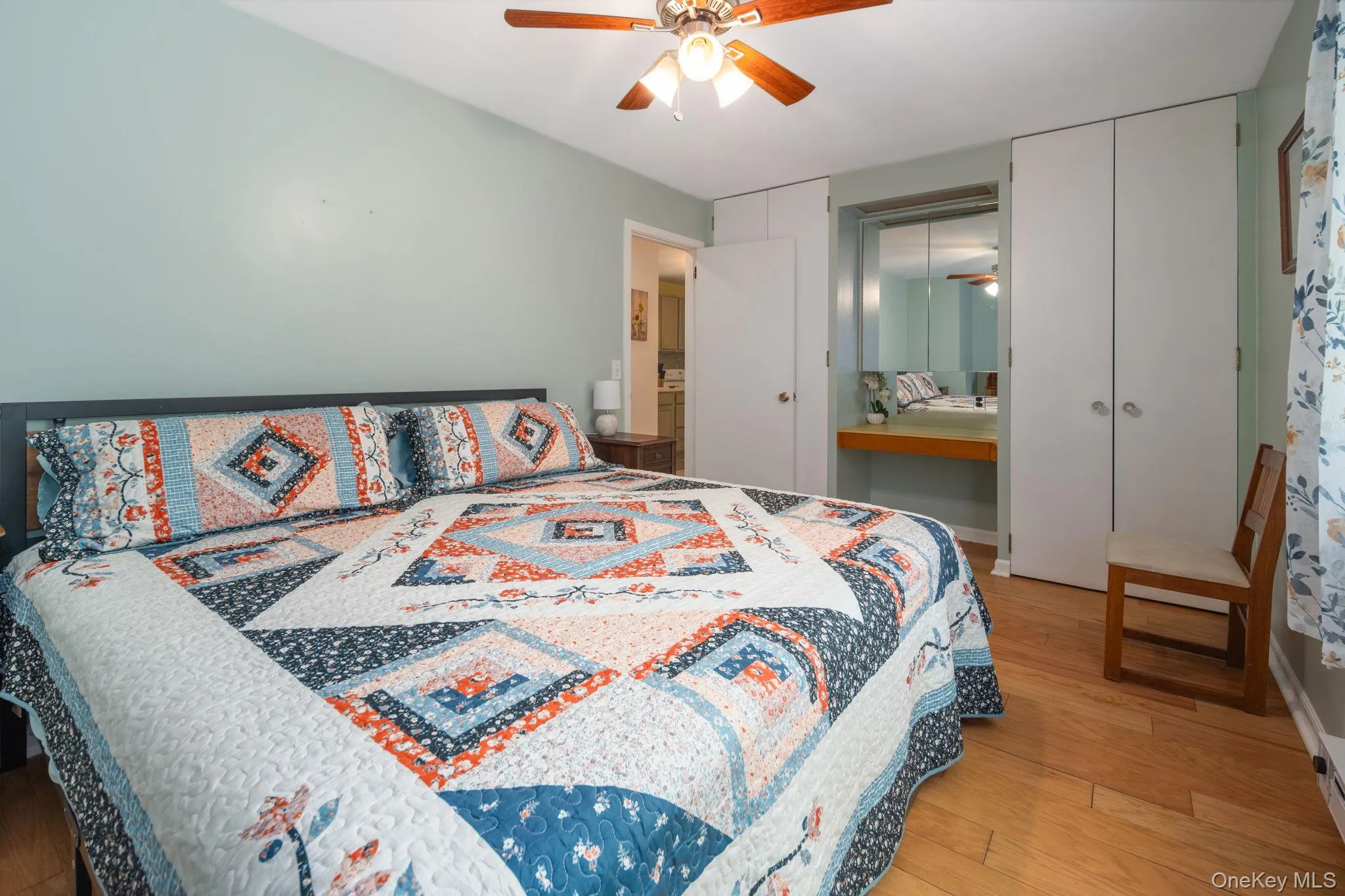 Wood-finish flooring, ceiling fan with light fixture, built-in cabinetry, and integrated vanity with mirror Wood-finish flooring, ceiling fan with light fixture, built-in cabinetry, and integrated vanity with mirror